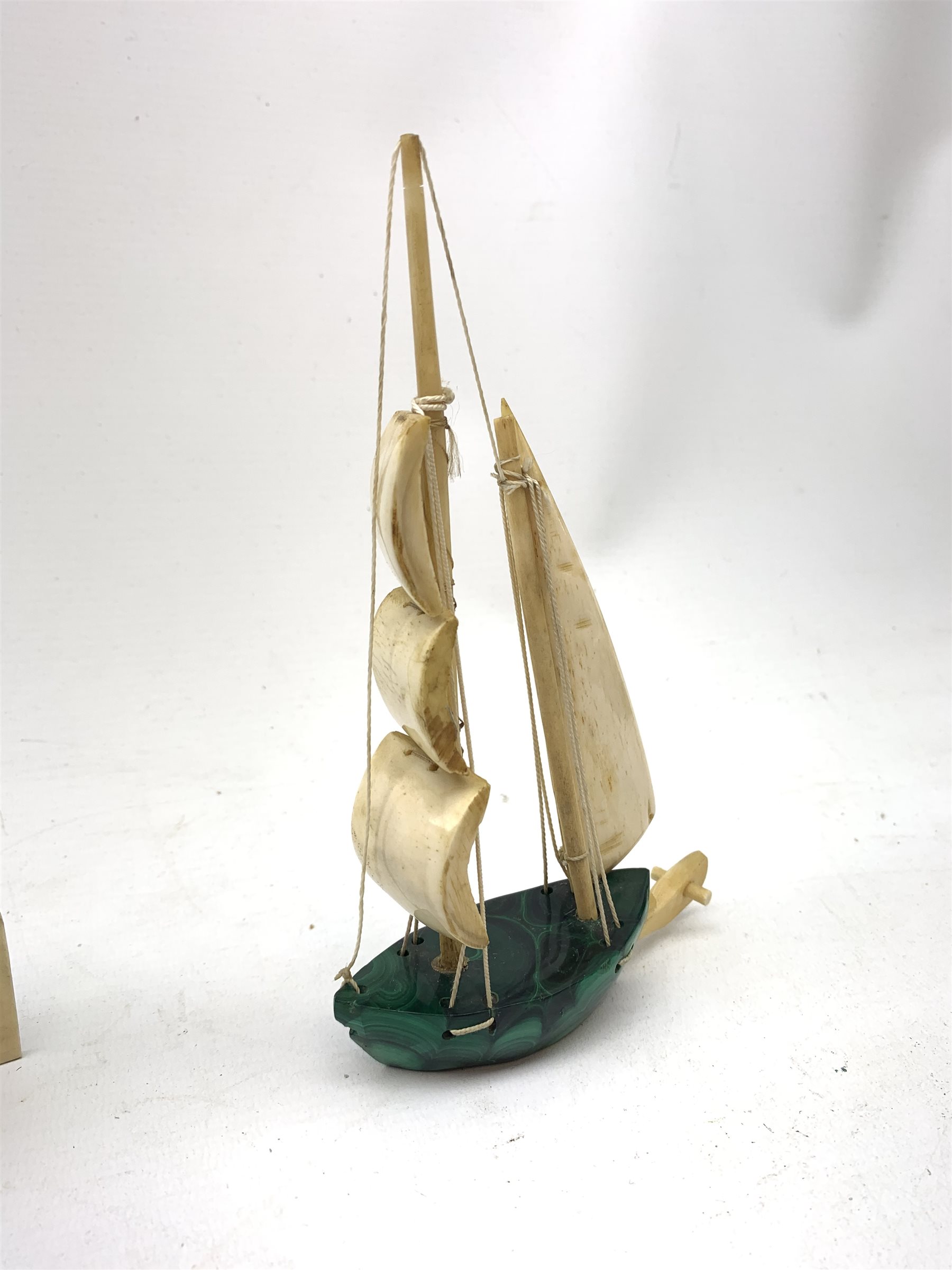 A Japanese carved ivory model of a sailing boat, surmounted by three carved figures (a/f), L22.5cm, together with a smaller sail boat with malachite hull and ivory sails and rudder, H18cm. 