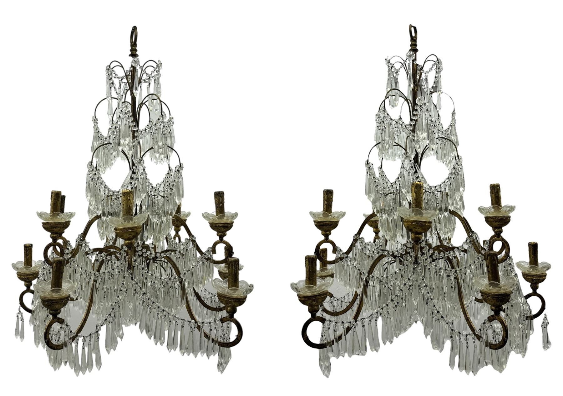 India Jane Interiors - pair of contemporary gilt bronze and crystal chandeliers, the framework featuring scrolling arms and garlands of crystal beads, each with twelve candle-style light fixtures with scalloped glass bobeches, adorned with multiple tiers of cut glass prisms, terminating in a central finial with a suspension loop