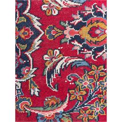 Large Persian Kashan crimson ground carpet, central floral medallion surrounded by swirling leafy branches and palmettes, enclose by floral pattern spandrels, the indigo border with overall scrolling design decorated with palmettes, within guard stripes 