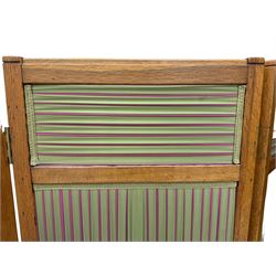 Edwardian oak and fabric folding screen, featuring three panels with oak frames, one side covered in green striped fabric with decorative trim, the reverse side in pink moiré effect fabric, connected by brass hinges