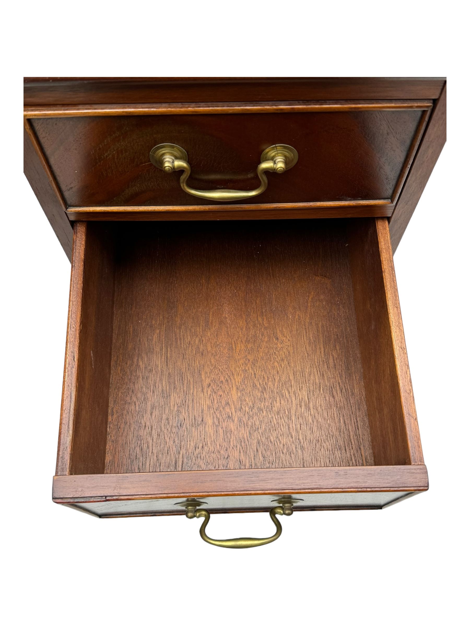 Late 20th century mahogany corner desk, leather inlaid top with gilt tooling, central frieze drawer flanked by two banks of four graduated drawers, raised on shaped bracket supports 