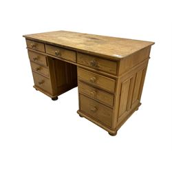 Waxed pine twin pedestal desk, rectangular top over nine drawers, on compressed bun feet 