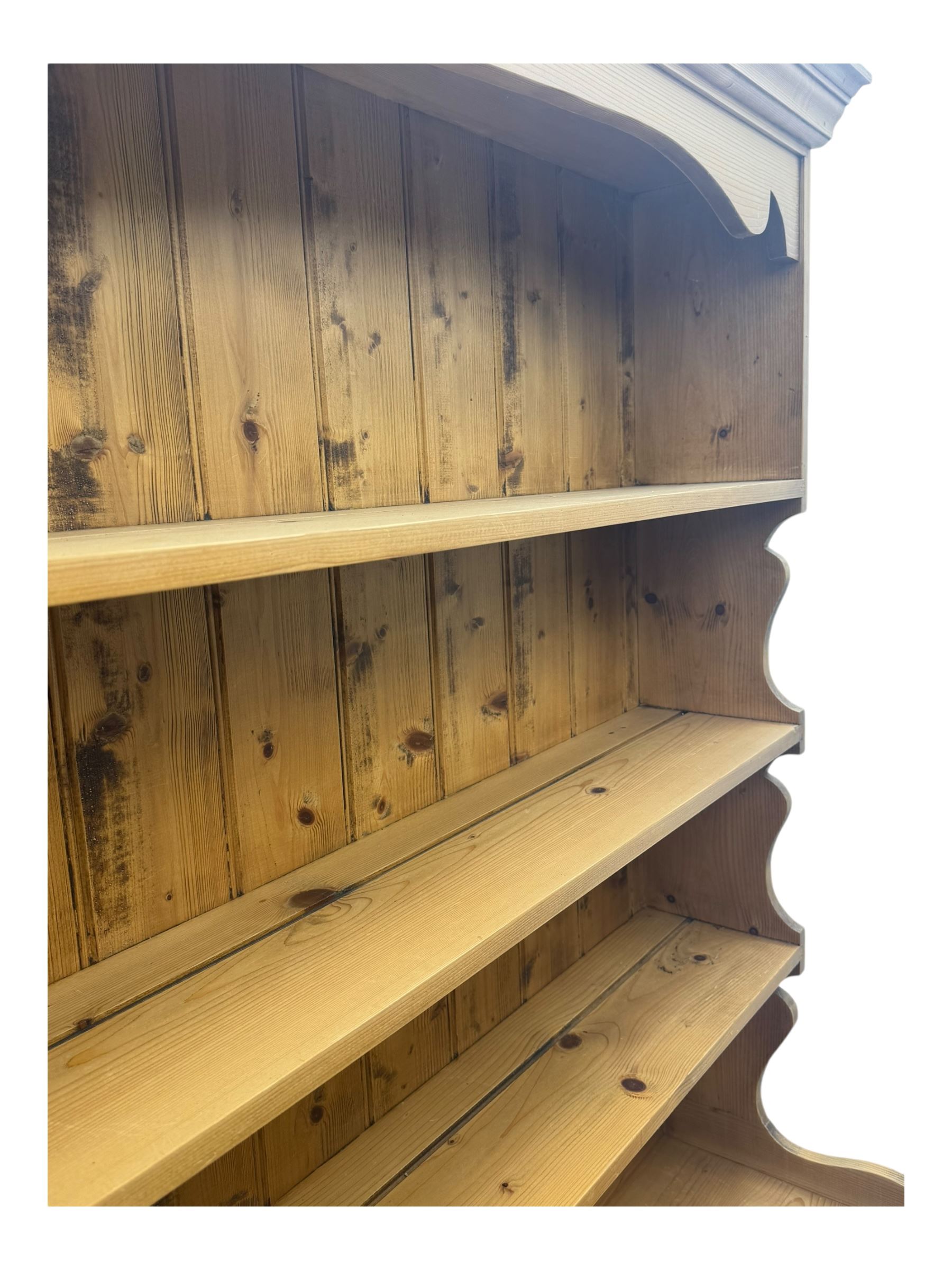 Large traditional pine dresser, shaped cornice over three open shelves, base fitted with four drawers above four panelled cupboards, each with turned wooden knobs, on plinth base