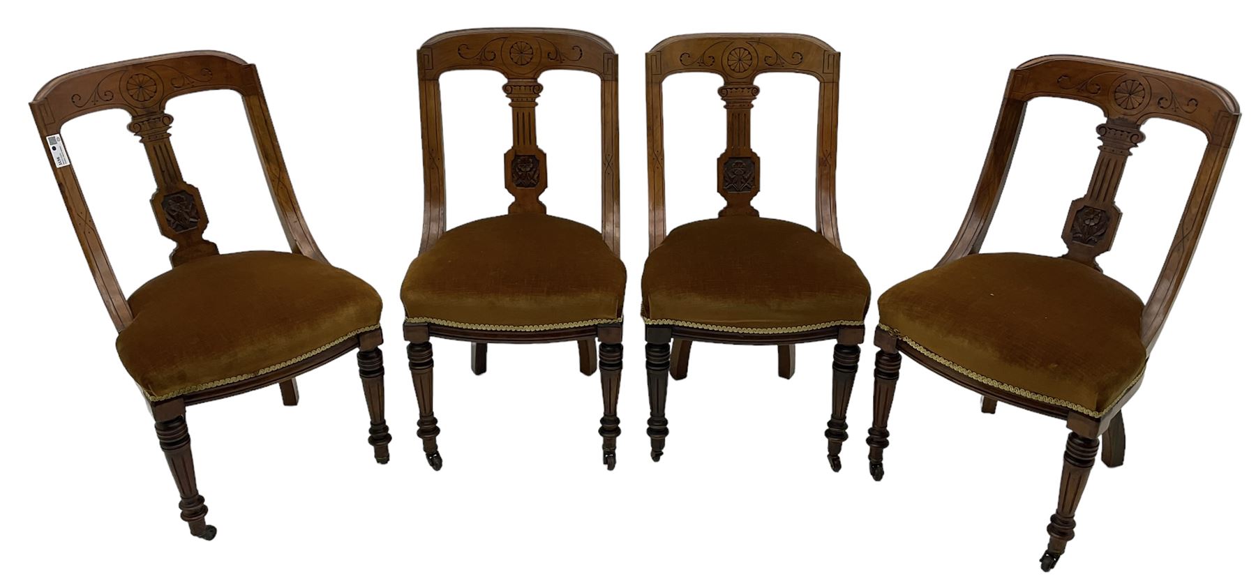 Set of four late Victorian walnut dining chairs, carved with stylised floral decoration and scrolling branches, upholstered seat, on turned and fluted supports 