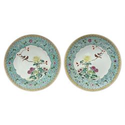 Pair of mid 20th century Chinese Qianlong Nian Zhi Famille Rose chargers, each decorated with two red crested birds perched upon a branch above blossoming pink and yellow peonies and chrysanthemums, within a turquoise border decorated with stylised flowers and scrolls, and yellow outer border, each with Qianlong Nian Zhi mark beneath, D33cm