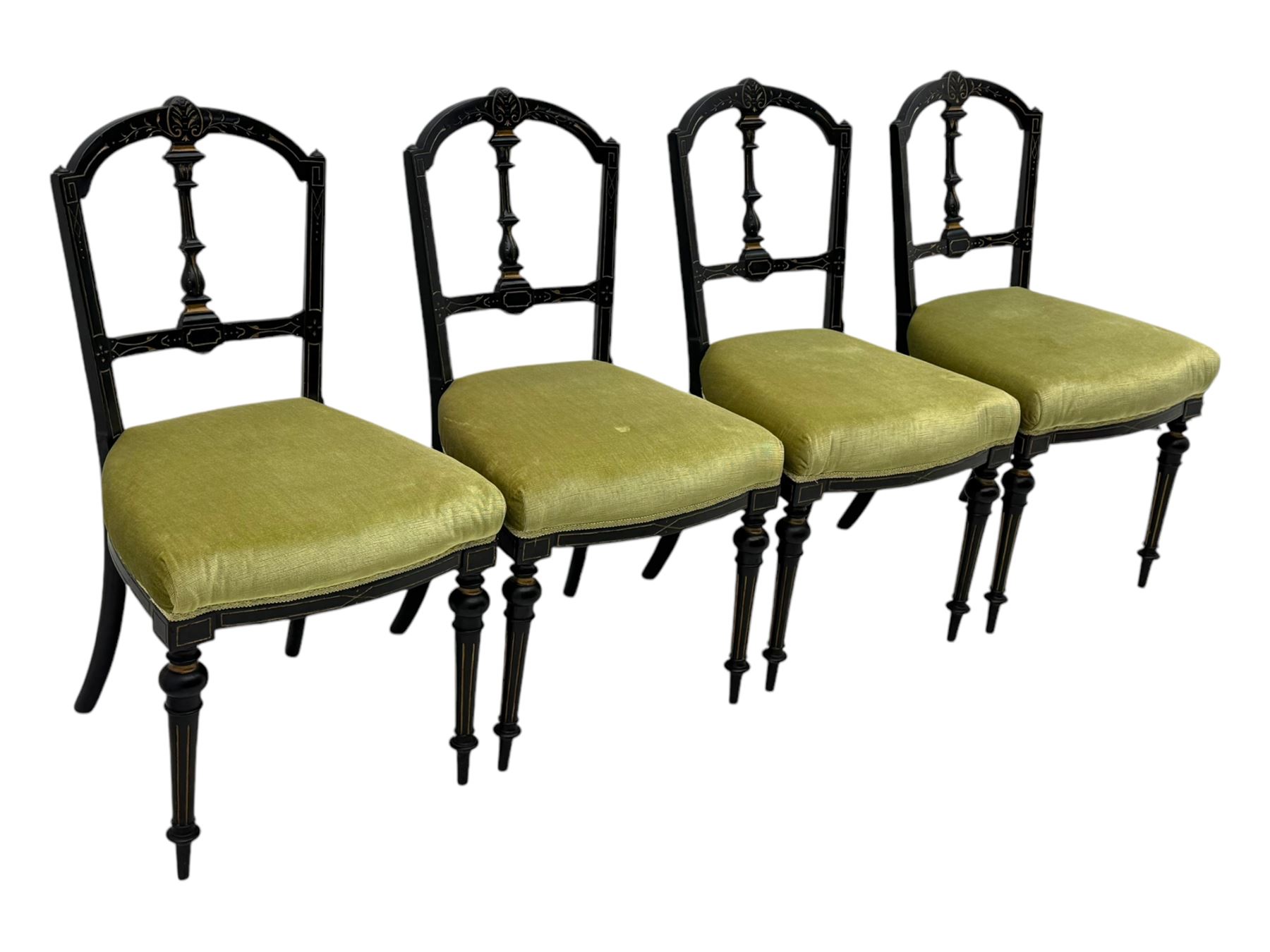 Set of four late Victorian ebonised dining chairs, decorated with carved and gilt foliate decoration, upholstered seats, on turned and fluted front supports 