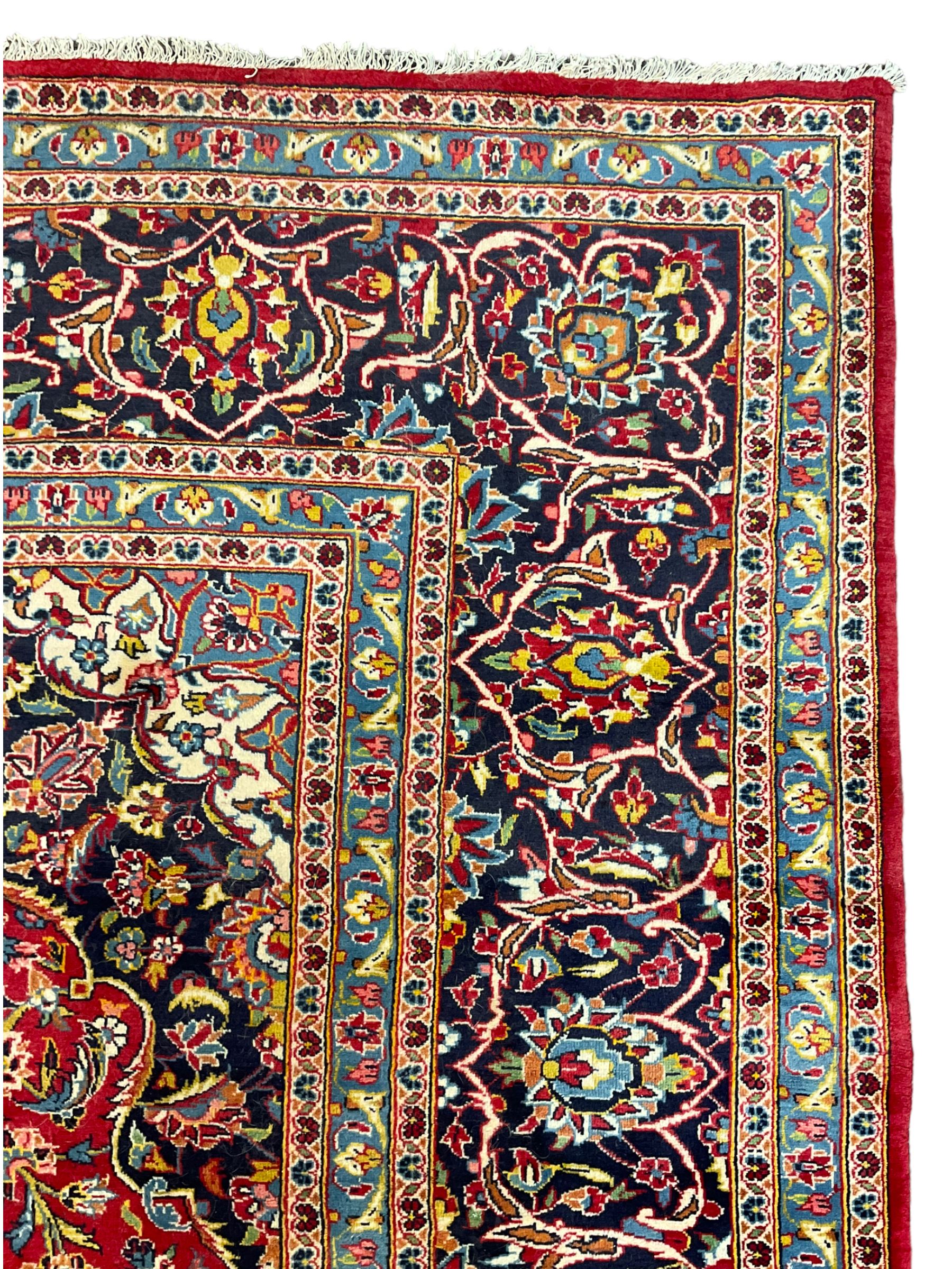 Persian Kashan crimson ground carpet, floral design central medallion surrounded by trailing leafy branches and stylised plant motifs, multi-band border with repeating floral design