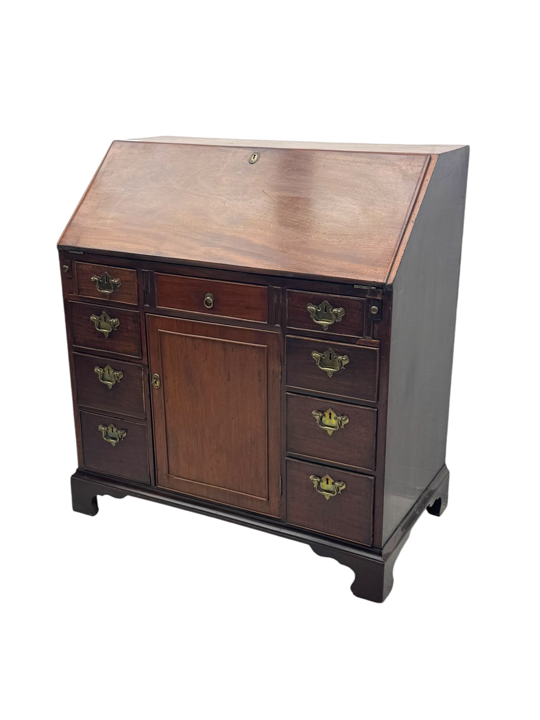 George III mahogany bureau, the fall-front enclosing fitted interior with pigeonholes and central cupboard, over an arrangement of nine short drawers surrounding a central cupboard, on shaped bracket feet