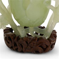 Chinese green jade magnolia form vase, supported on a leafy stem, with flowers and butterflies, on a pierced and carved hardwood stand, H15cm x W14cm