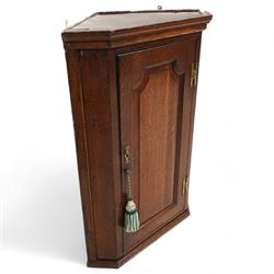 George III oak wall hanging corner cupboard, shaped fielded panelled door enclosing shelves and spice drawers