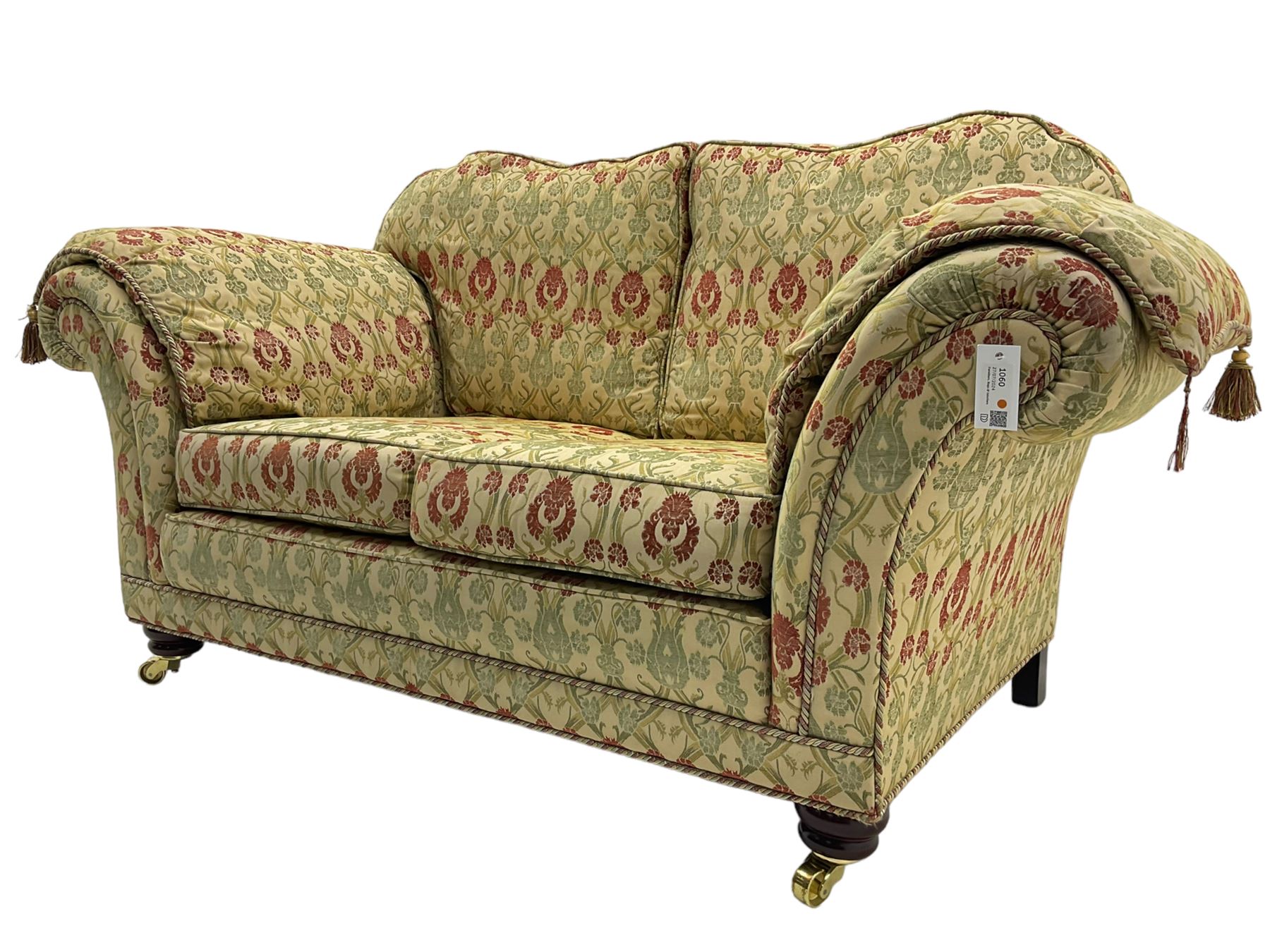 Traditional design two seat sofa, high back with scrolled arms, upholstered in beige fabric with red and green damask motifs, on castor supports (L178cm, D100cm, H89cm); matching armchair (L109cm, D89cm, H89cm)