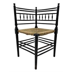 In the manner of William Morris - Arts & Crafts period corner chair, swell turned horizontal rails with balustrade back, rush seat on ring turned supports, black paint finish 