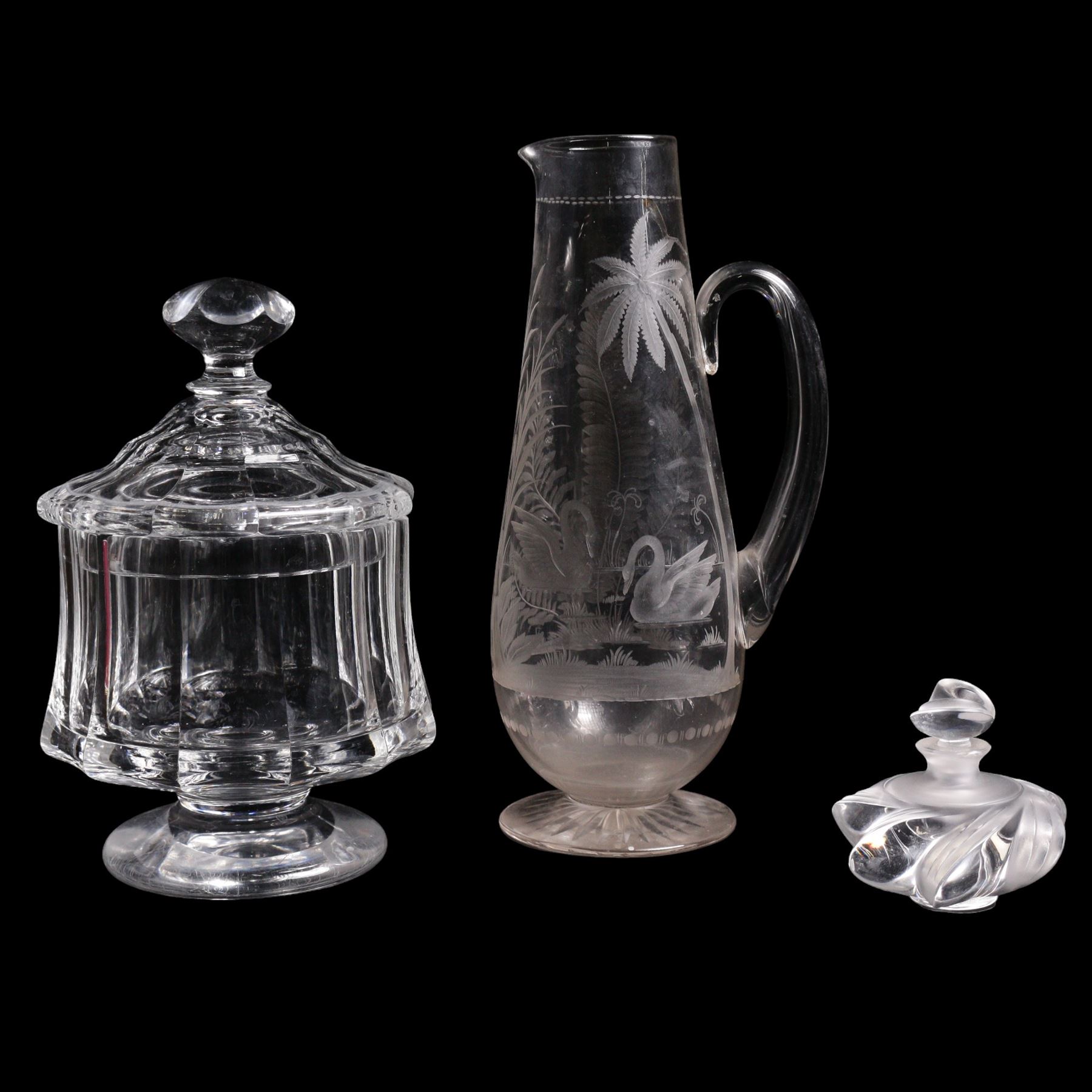 19th/ early 20th century crystal water jug, probably Stourbridge, of baluster form engraved with two Swans on a lake, amongst ferns, reeds and a palm tree, on circular pedestal star engraved foot, H28cm, heavy cut glass jar and cover on pedestal foot, together with a Lalique Samoa frosted glass scent bottle, signed Lalique, France, and labelled 11312 H8cm (3)