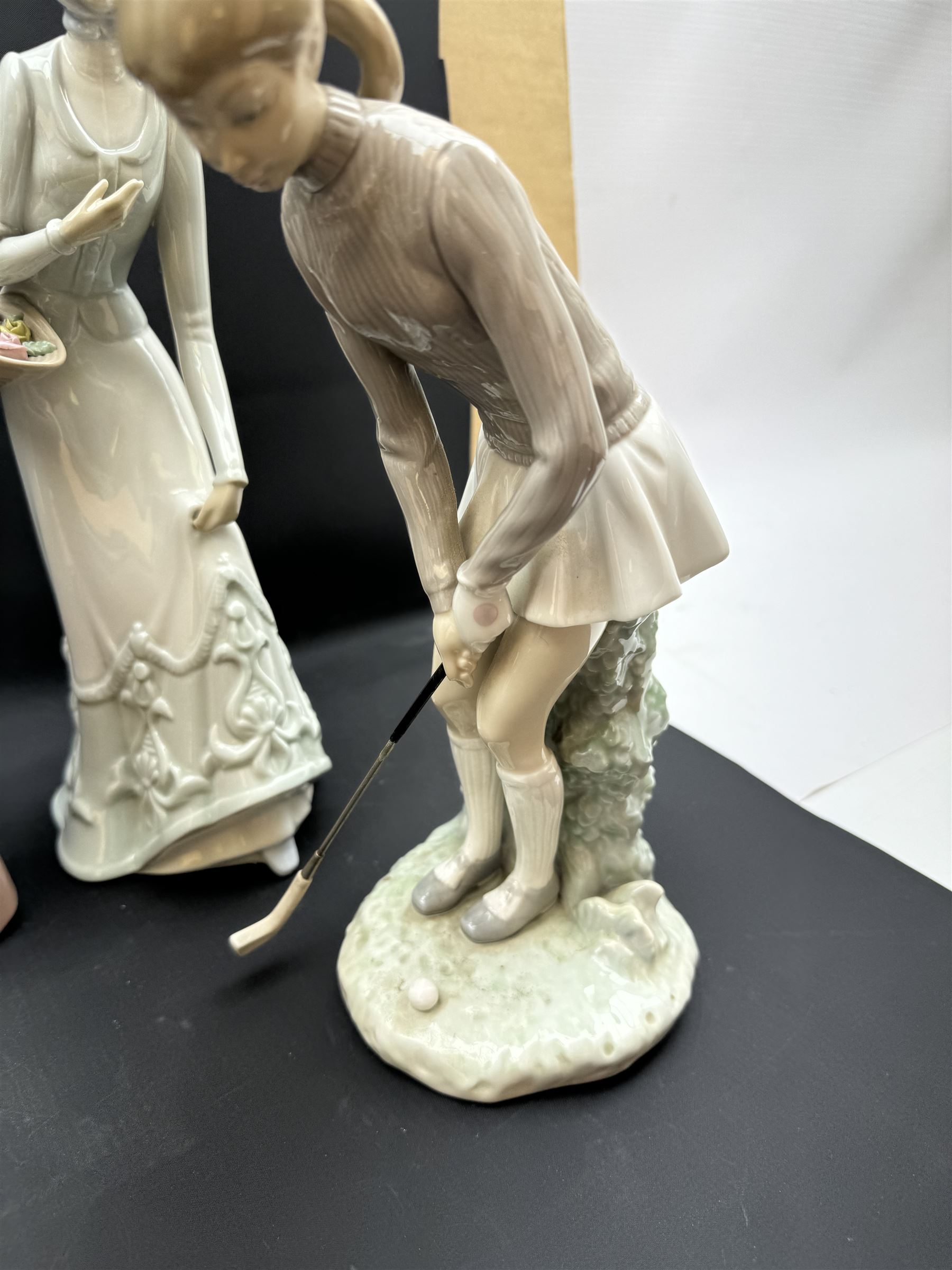 Group of Lladro figures, to include May Dance no 5662, examples modelled as a female golfer, young woman holding sheep in her arms, pair of figures in pink dressed holding sun hats, etc., together with two Nao figures and a further Spanish example, (11)