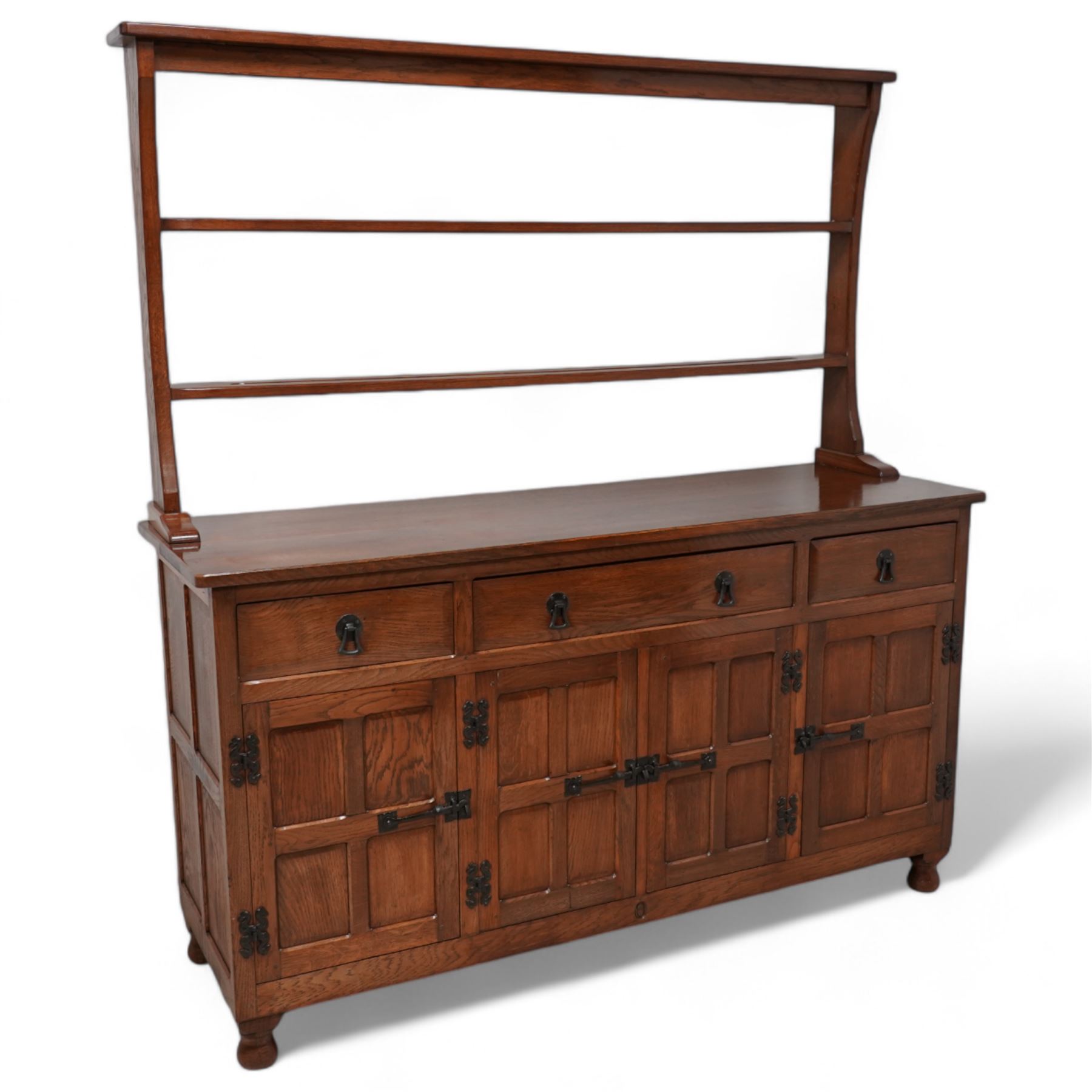 Acornman - oak dresser, raised two heights plate rack over three drawers and panelled cupboards, fitted with wrought metal fittings and handles, carved with acorn signature, by Alan Grainger, Brandsby, York 