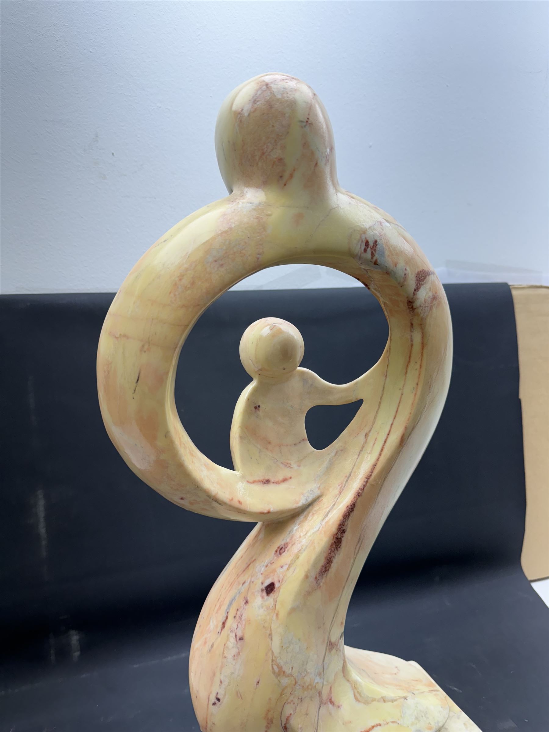 Abstract marble sculpture modelled as a mother and child on a rectangular base, H62cm