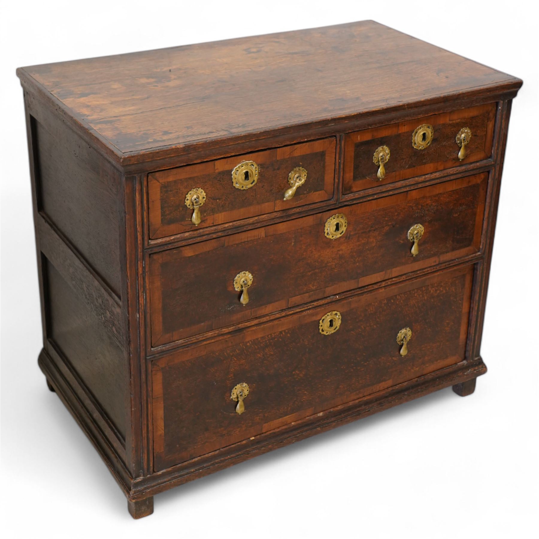 Early 18th century oak chest, rectangular top over two short and two long drawers with yew wood bands, shaped handles and escutcheons with drop handles, on stile supports 