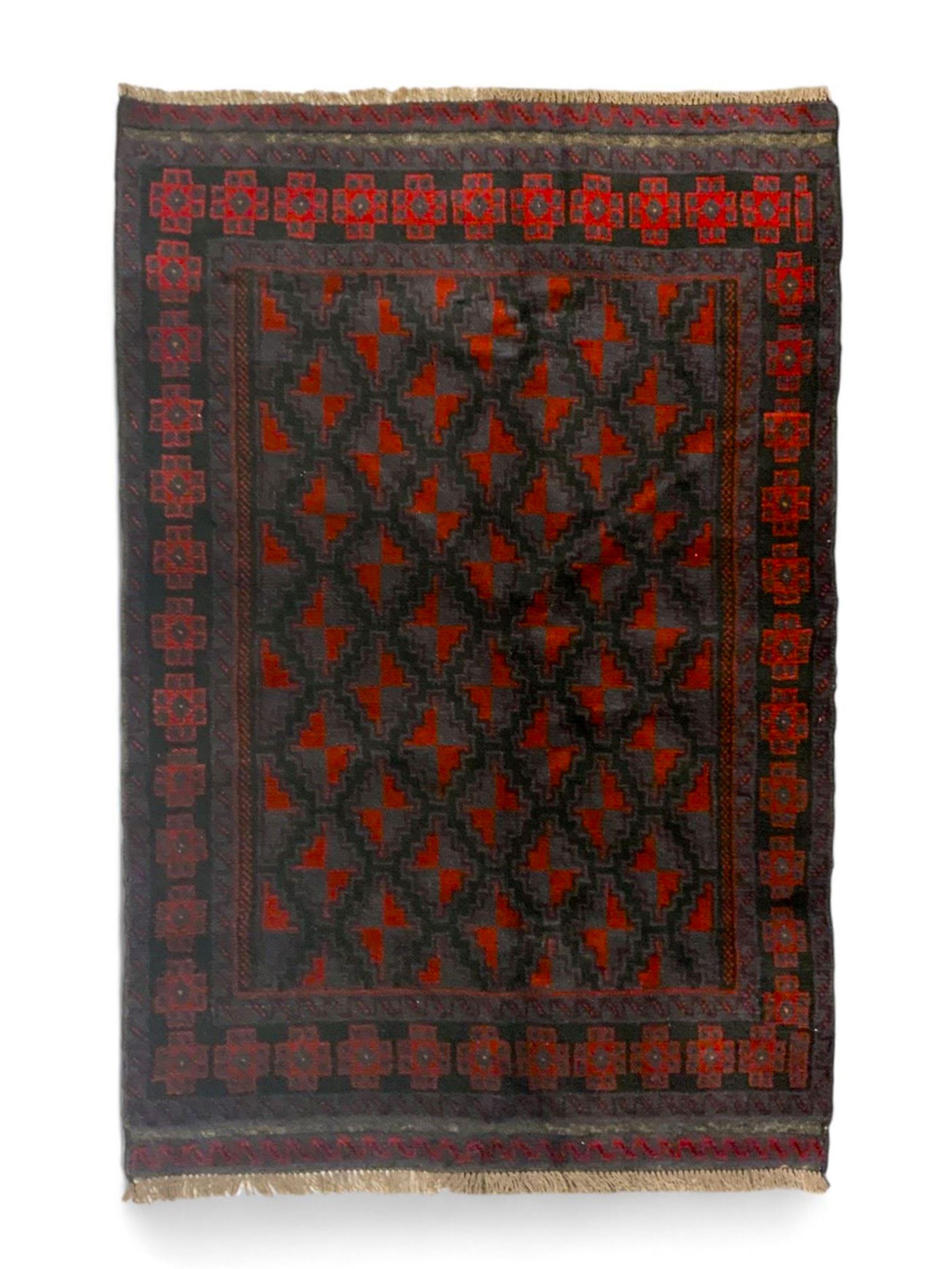 Baluchi indigo ground rug, the field decorated with all-over crimson and indigo lozenges, enclosed by geometric guard lines