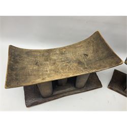 Two carved hardwood African head rests, each upon five supporting pillars and rectangular bases, tallest H21cm
