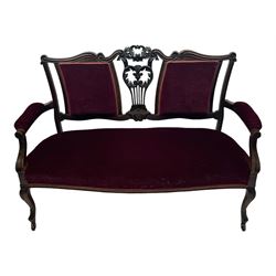 Late Victorian dark oak framed sofa, the backrests, seat and padded arms upholstered in deep red fabric, carved crest rail with scroll and foliate motifs supported by carved uprights, on cabriole supports with leaf carvings terminating in castors