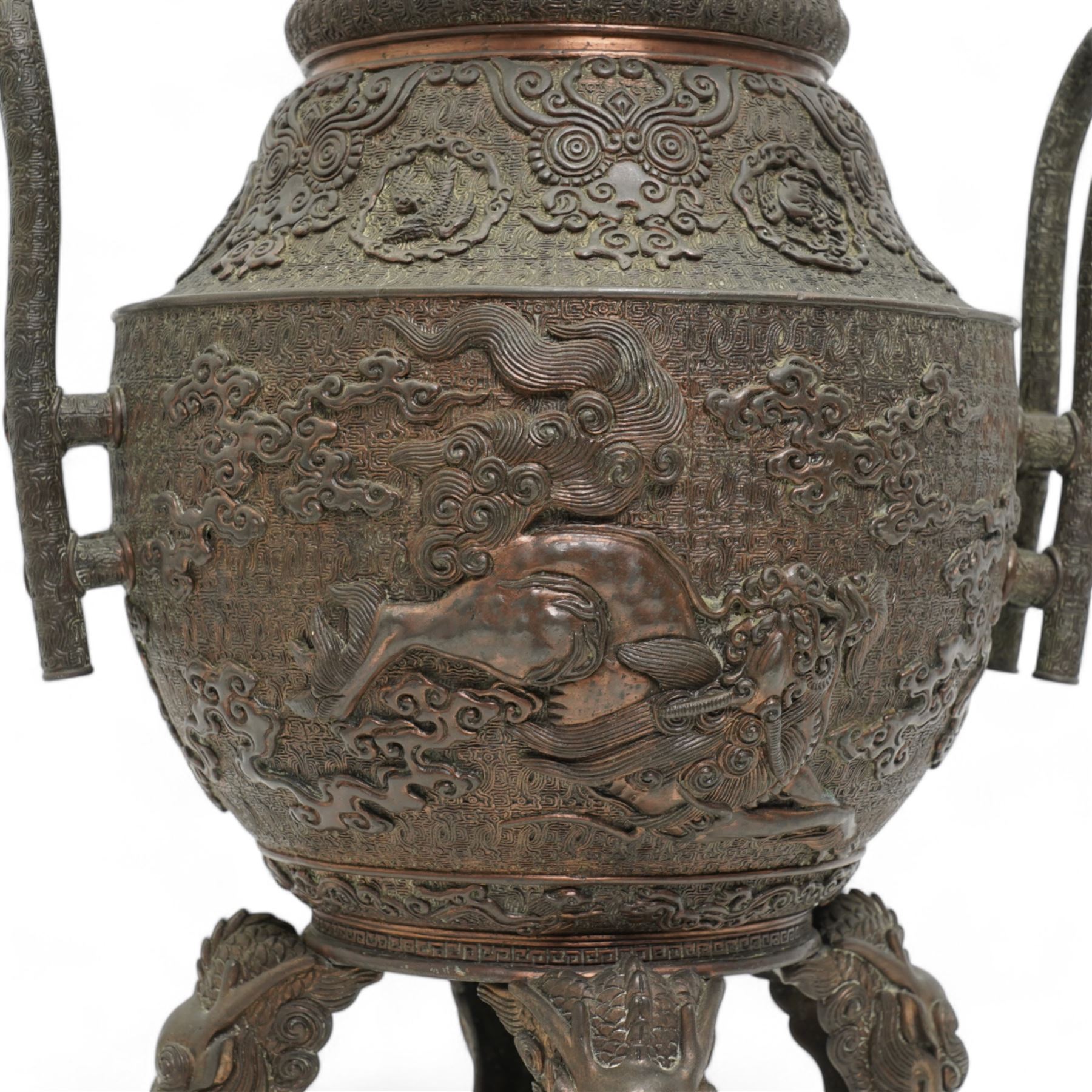 Large 19th century Japanese bronze koro, the ovoid body decorated in relief with phoenix and kylin amidst clouds, with two elongated loop handles and chrysanthemum finial, on four tall mask and tongue feet, impressed seal mark beneath, H44cm x W27cm 