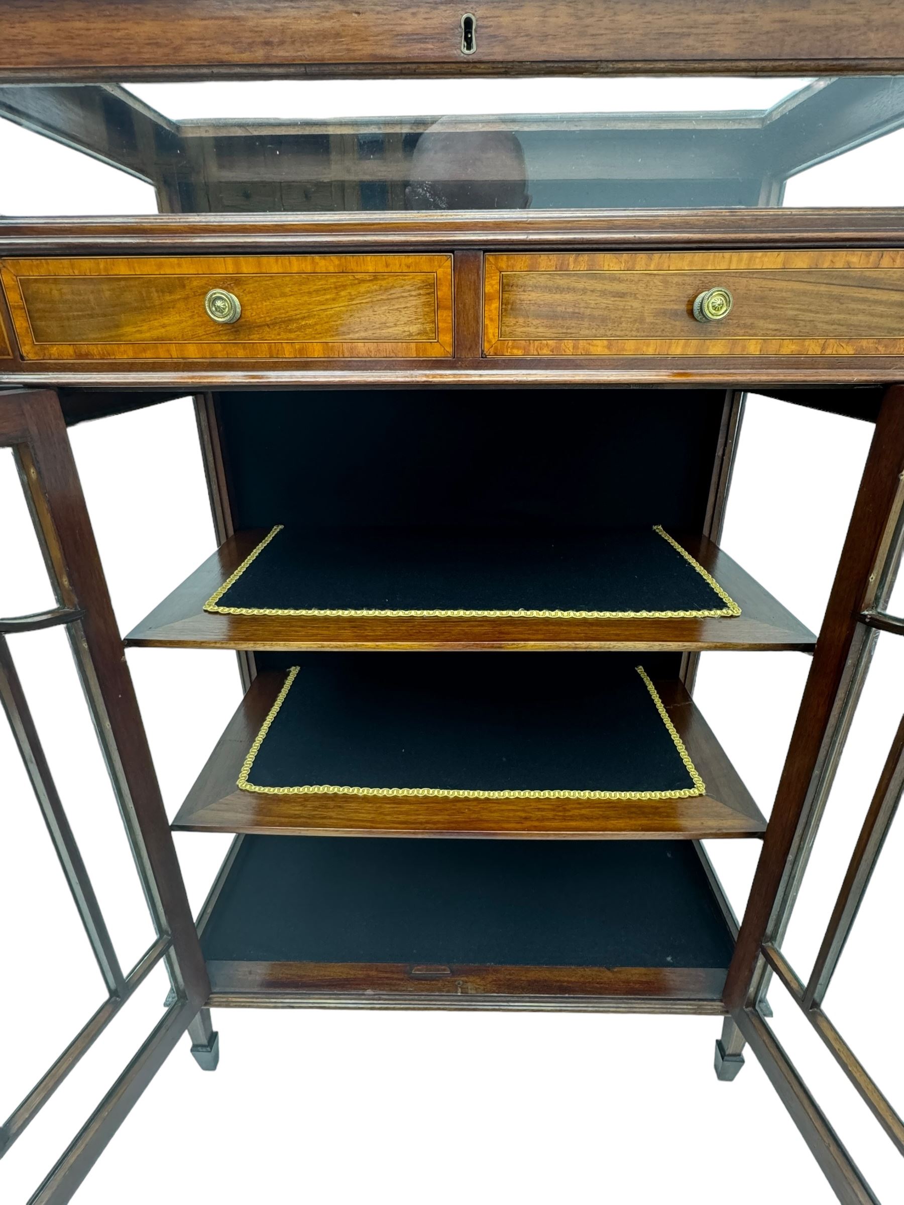 Edwardian mahogany bijouterie display cabinet, featuring satinwood inlay and crossbanding, hinged glazed top fitted with two banded drawers, over two astragal glazed doors enclosing black wool baize lined shelves with gold trim, supported by spade feet