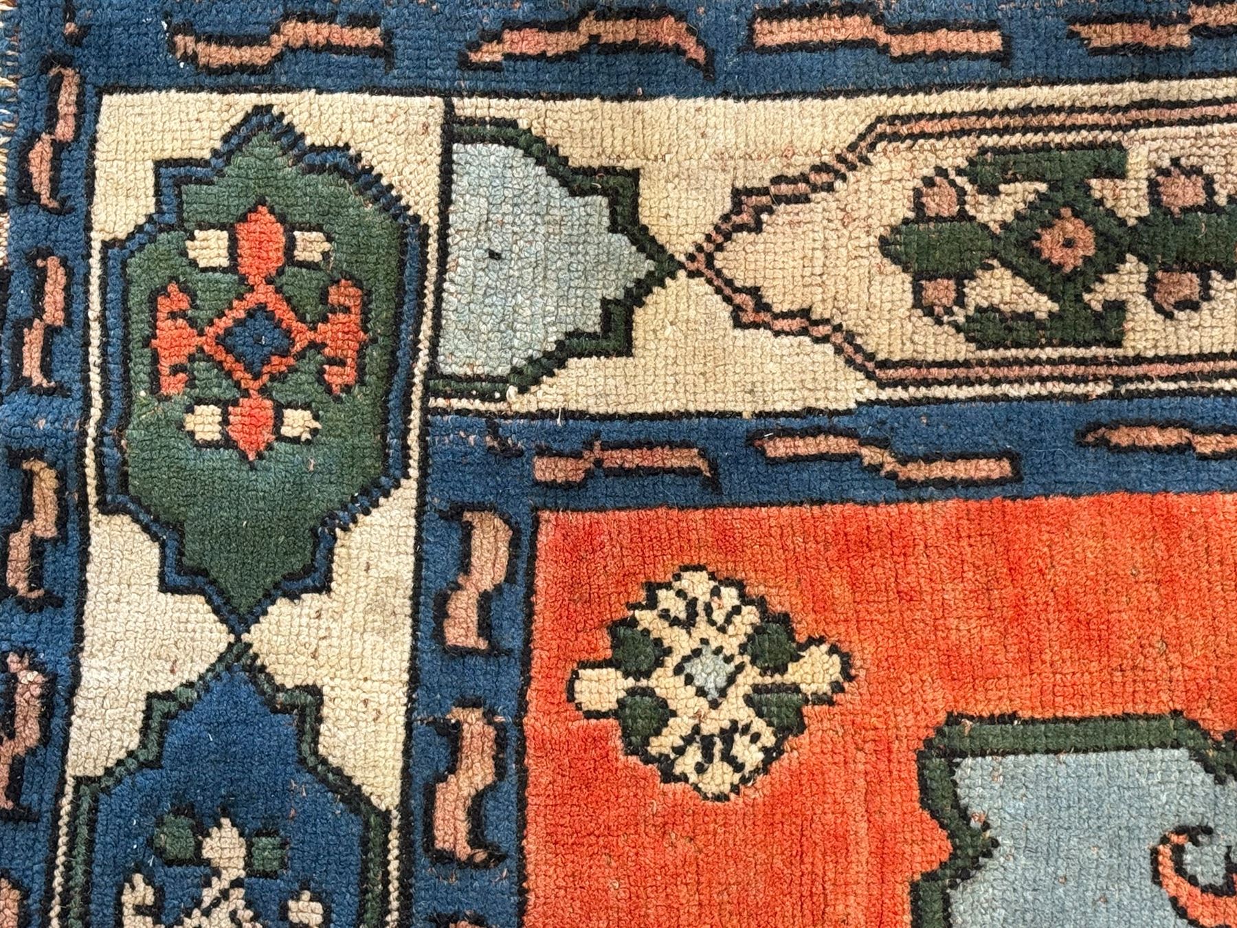 Turkish indigo ground rug, the shaped central field decorated with a central geometric stylised plant motif, enclosed with a guarded border decorated with contrasting motifs 