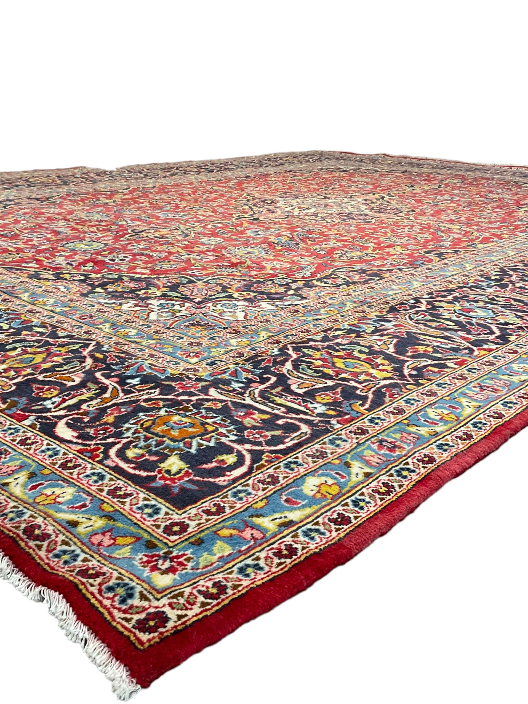 Persian Kashan crimson ground carpet, floral design central medallion surrounded by trailing leafy branches and stylised plant motifs, multi-band border with repeating floral design