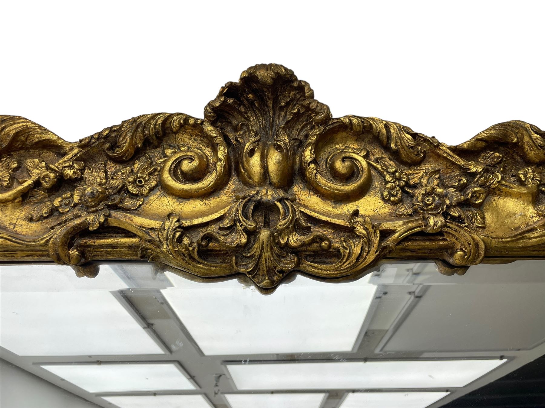 Large gilt framed rectangular wall mirror, shaped and moulded frame decorated with trailing curled acanthus leaves and flower head motifs, bevelled glass plate 