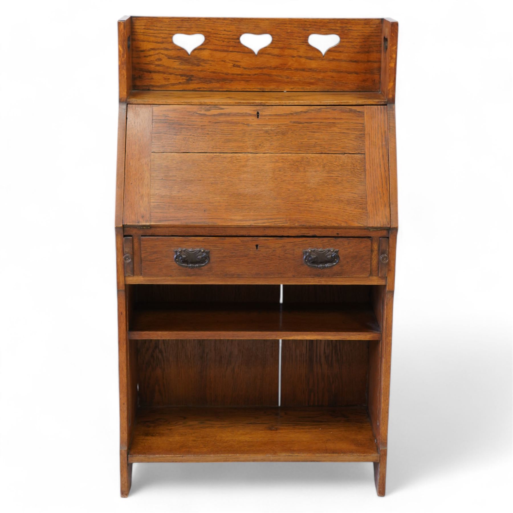 Possibly Liberty & Co - Arts & Crafts light oak bureau, the three-quarter raised gallery pierced with hearts, over a fall-front enclosing fitted interior with correspondence and pigeonholes, fitted with single drawer with poppy decorated handles, single open shelf to base