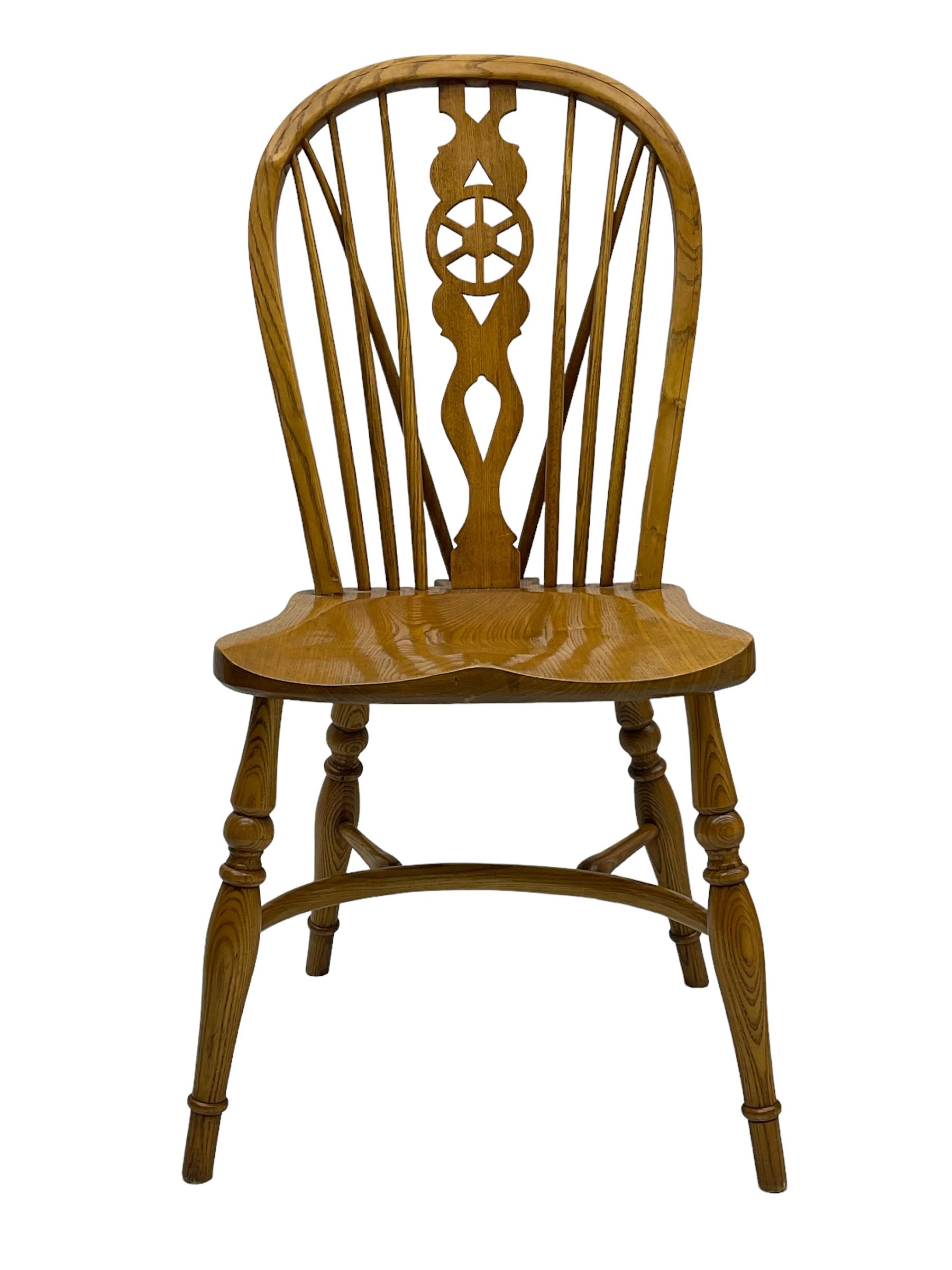 Set of four elm Windsor dining chairs, hoop and stick back with shaped wheel splat, dished seat on turned supports united by crinoline stretcher 