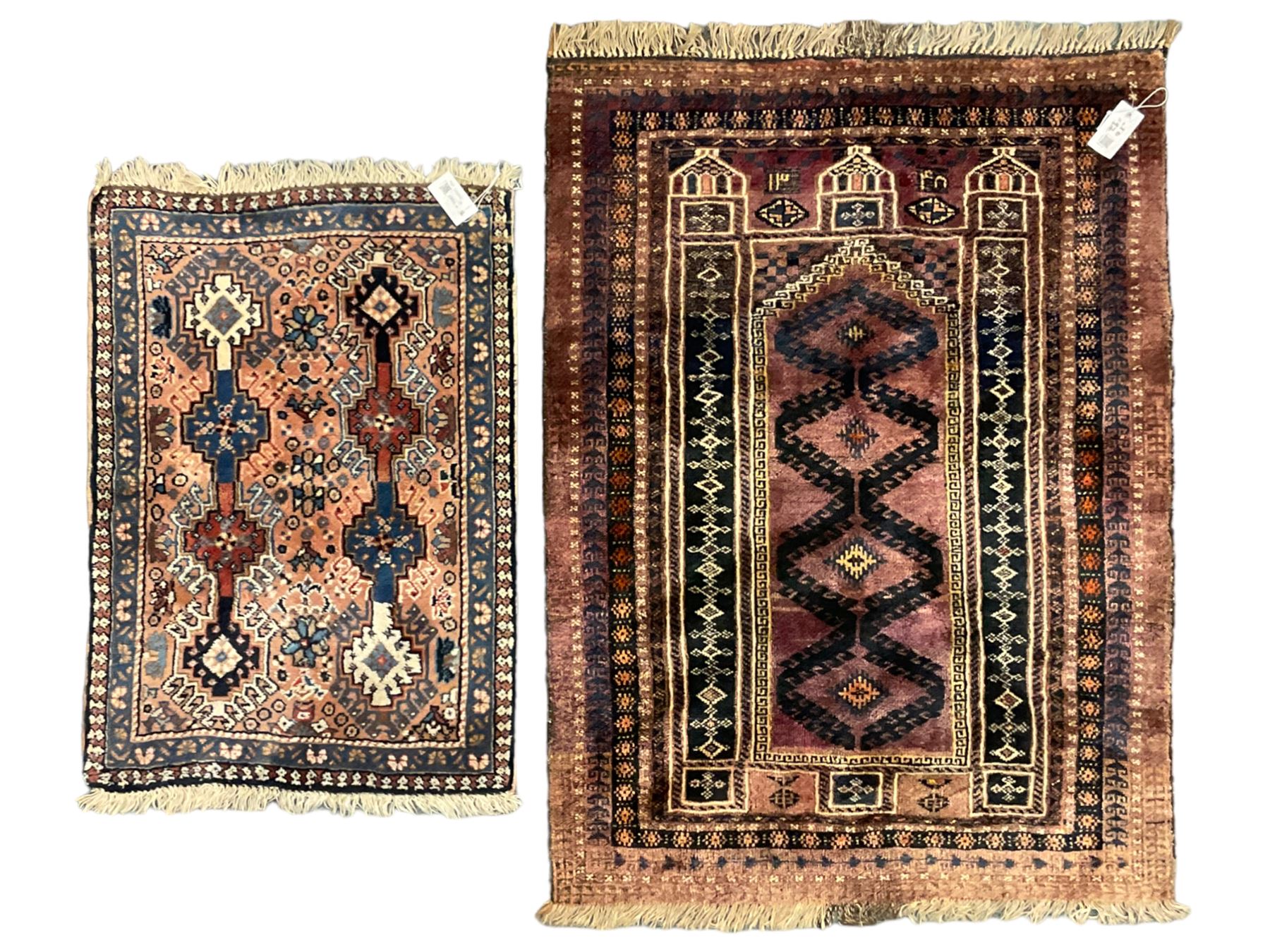 Persian prayer purple ground, decorated with three pointed buildings over tailing lozenge patterned field (111cm x 82cm); and a small Persian rug or mat, overall geometric design (81cm x 56cm)