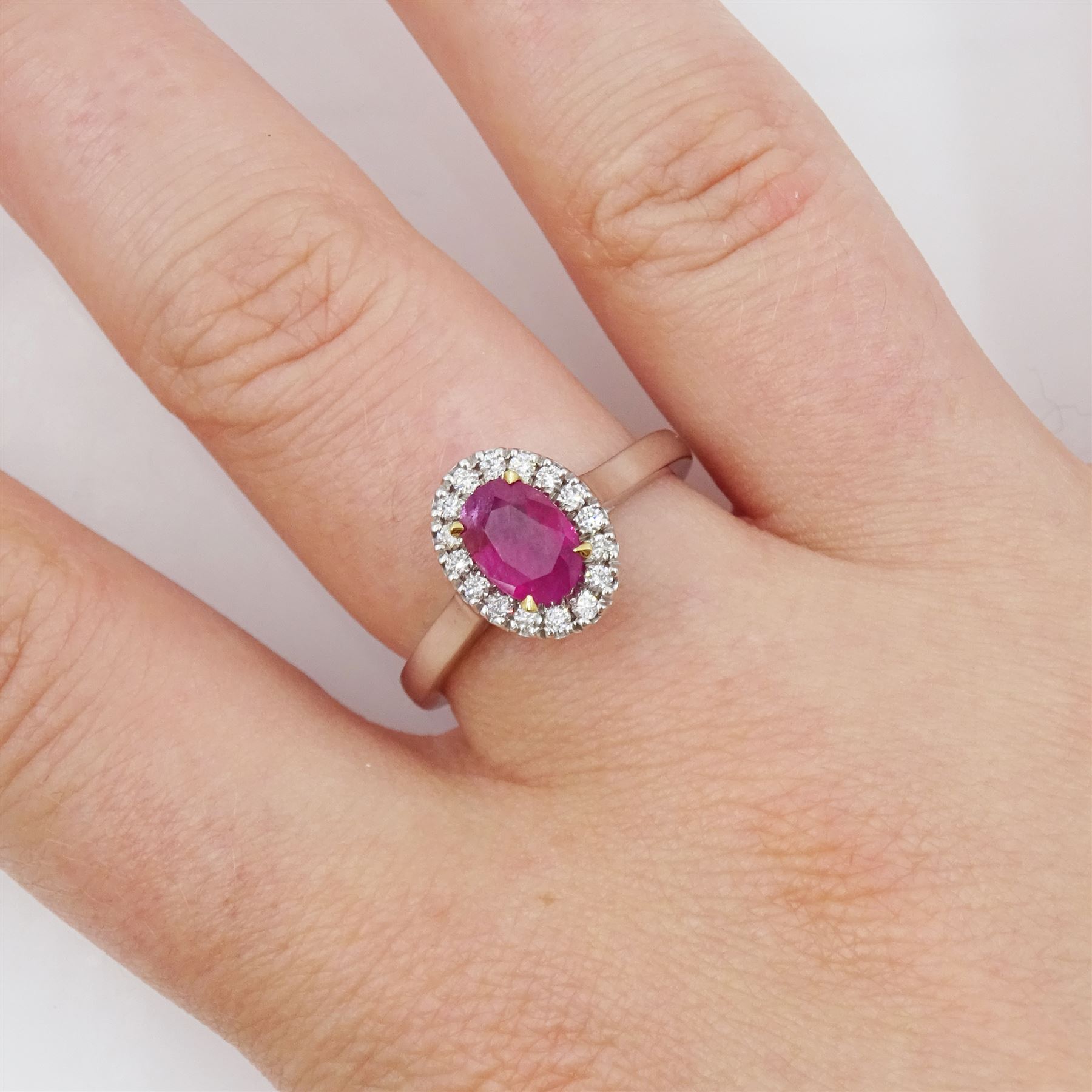 18ct white gold oval cut ruby and round brilliant cut diamond cluster ring, hallmarked, ruby approx 0.85 carat, total diamond weight approx 0.15 carat