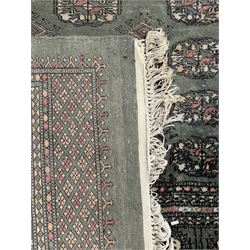 Pakistani Bokhara green ground rug, the field decorated with rows of repeating gul motifs, the main border featuring a series of smaller gul designs and geometric patterns, framed by multiple guard stripes