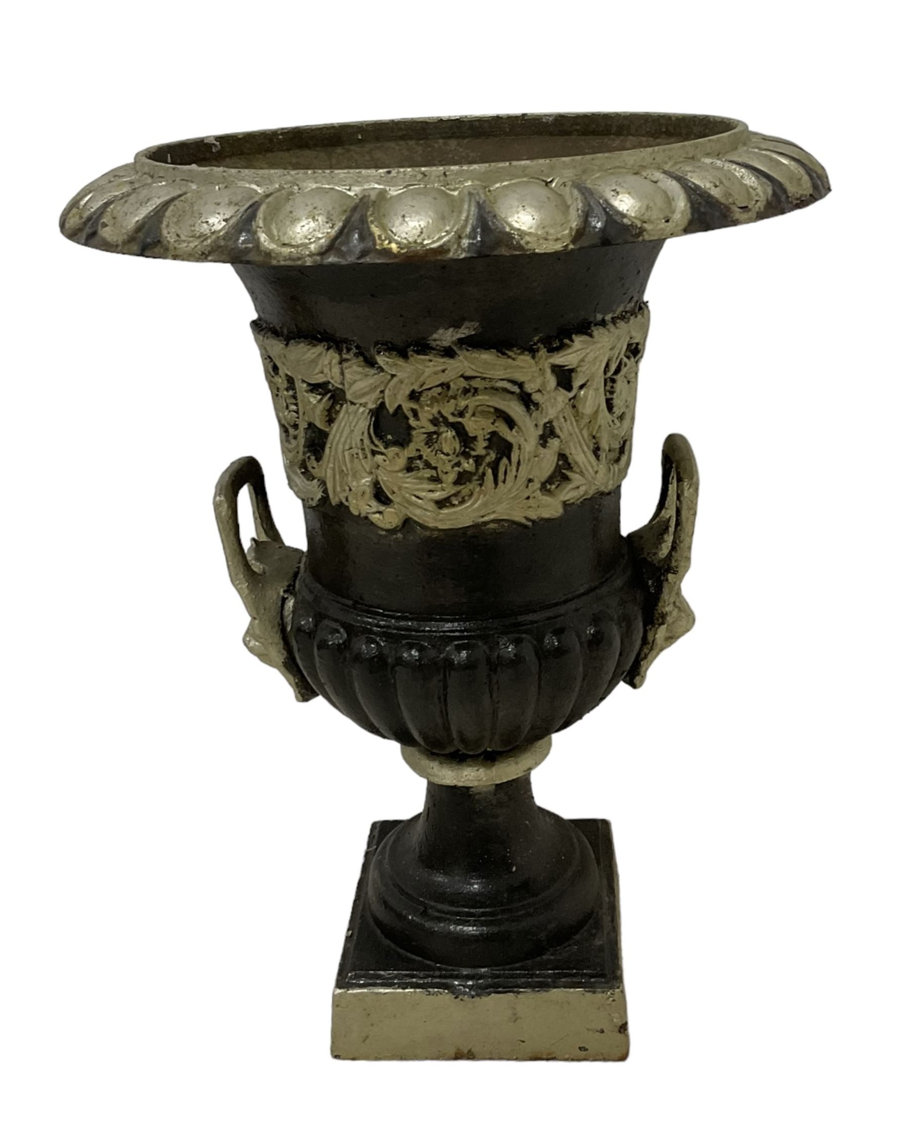 20th century cast iron Campana-shaped urn on plinth, with scrolling foliate relief decoration, in ebonised and silver painted finish