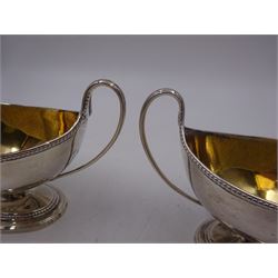 Pair of George III twin handled silver salts, of navette form with beaded rim and twin whiplash handles, each engraved to body with crest, upon stepped oval foot, London 1784, H8.5cm