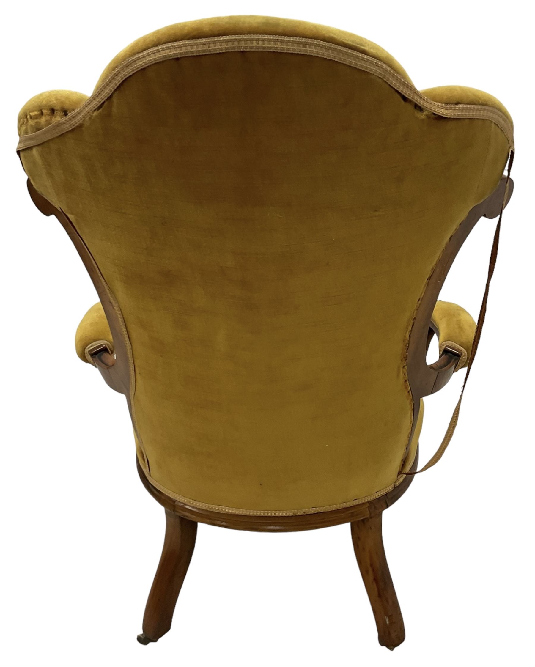 19th century walnut framed open armchair, scallop shaped back with c-scroll uprights, upholstered in yellow buttoned velvet fabric with sprung seat, arm terminals carved with acanthus leaves, raised on scrolling cabriole supports with castors