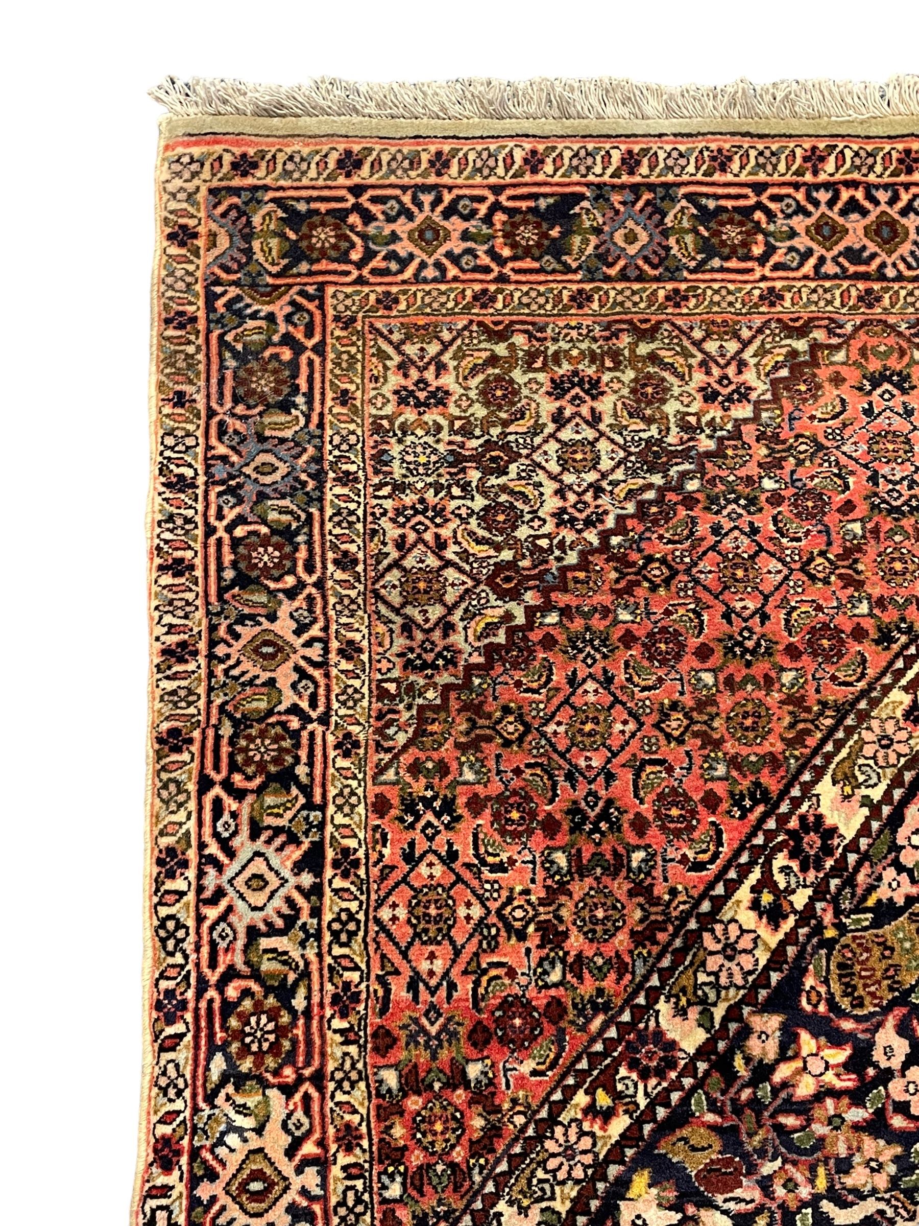 Persian Bidjar peach ground rug, the field decorated with repeating Herati motifs surrounding an off-centre lozenge medallion, decorated with grazing deer and peacock motids, the field border decorated with repeating stylised plant motifs, multiple floral design guard bands