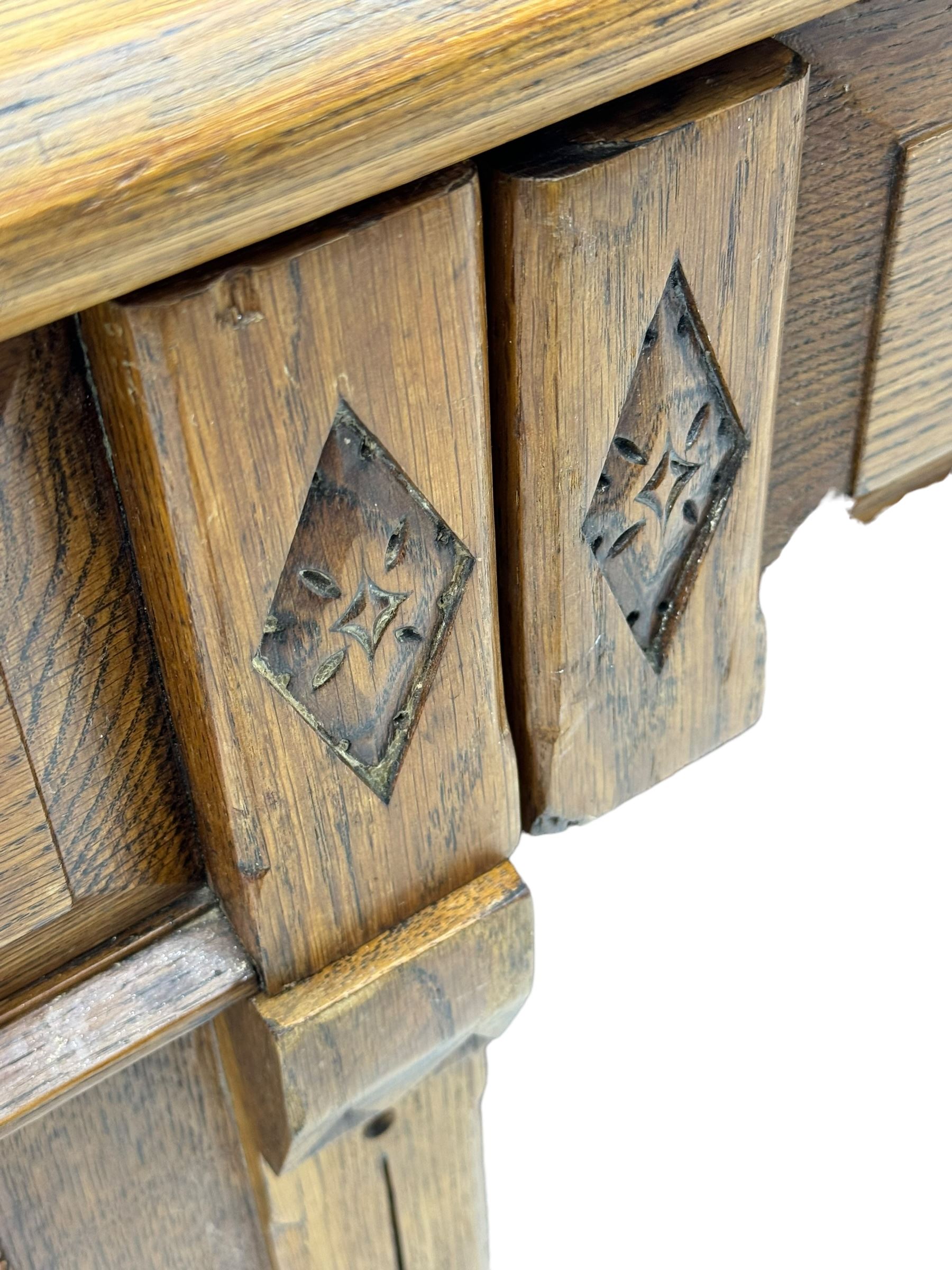 Late Victorian oak twin pedestal desk, chamfered rectangular top over three convex front edge drawers and two panelled cupboards, flanked by carved supports with roundels and diamond motif, on bracketed plinth base