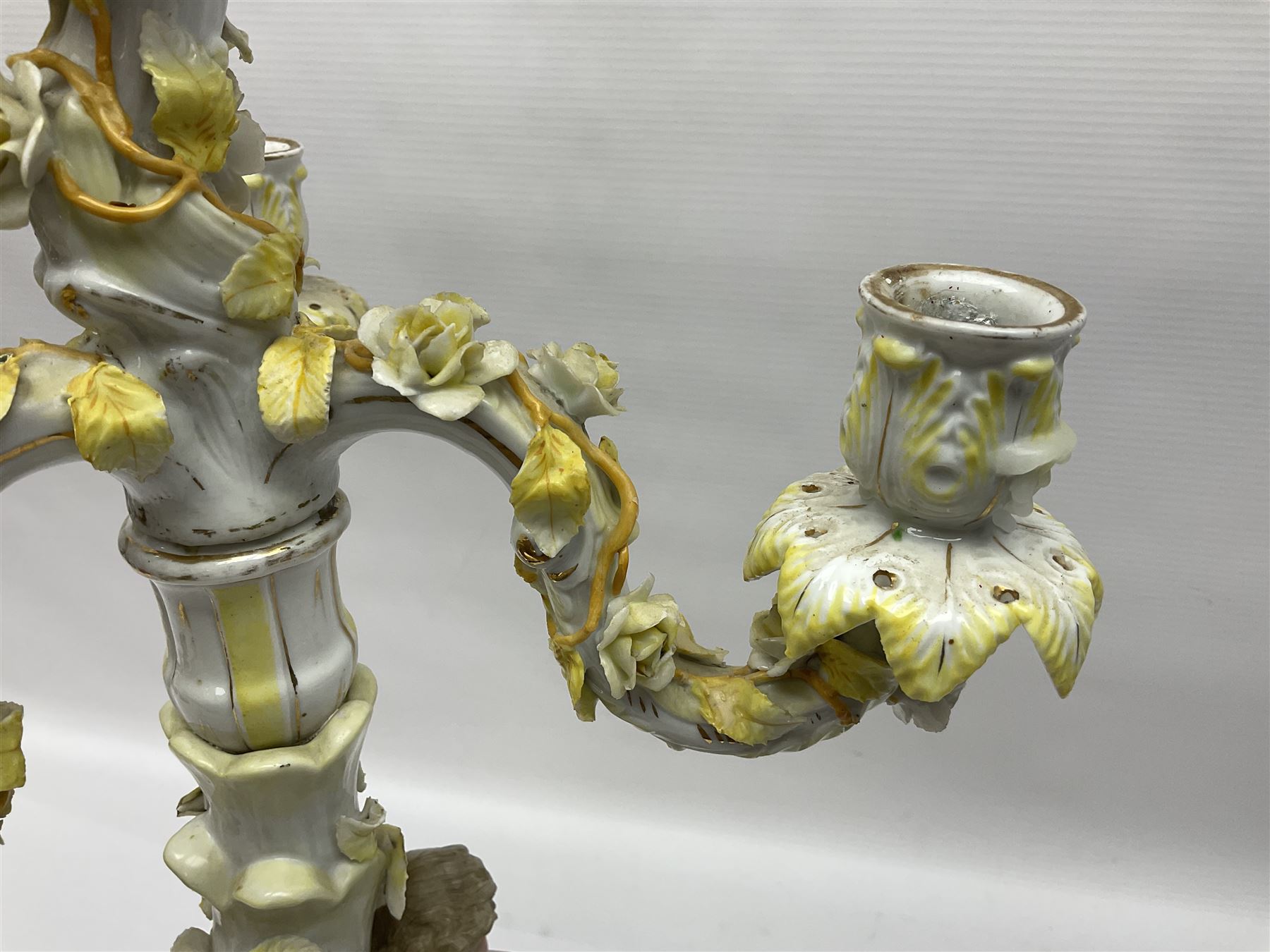 Dresden style candelabra, the central stem bordered by three branches, decorated with cherubs and yellow roses, H48cm