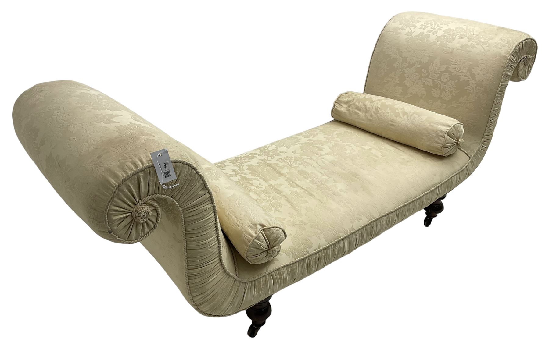 Victorian mahogany framed window seat day bed, the scrolled arms and seat upholstered in ivory foliate patterned damask fabric with matching ropetwist piping, raised on turned supports with castors