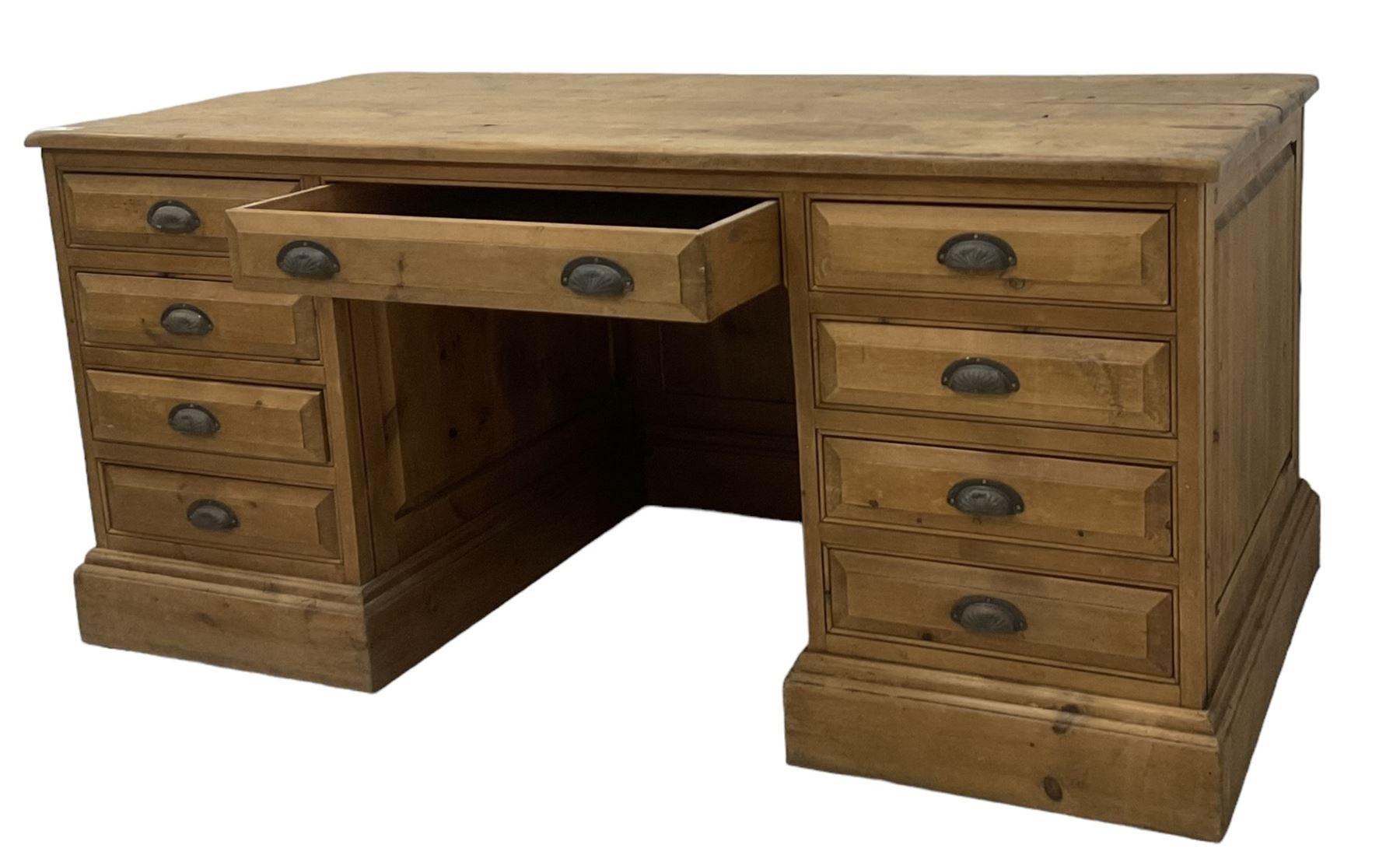 20th century waxed pine kneehole desk, rectangular top over nine drawers with cup handles, on moulded plinth base