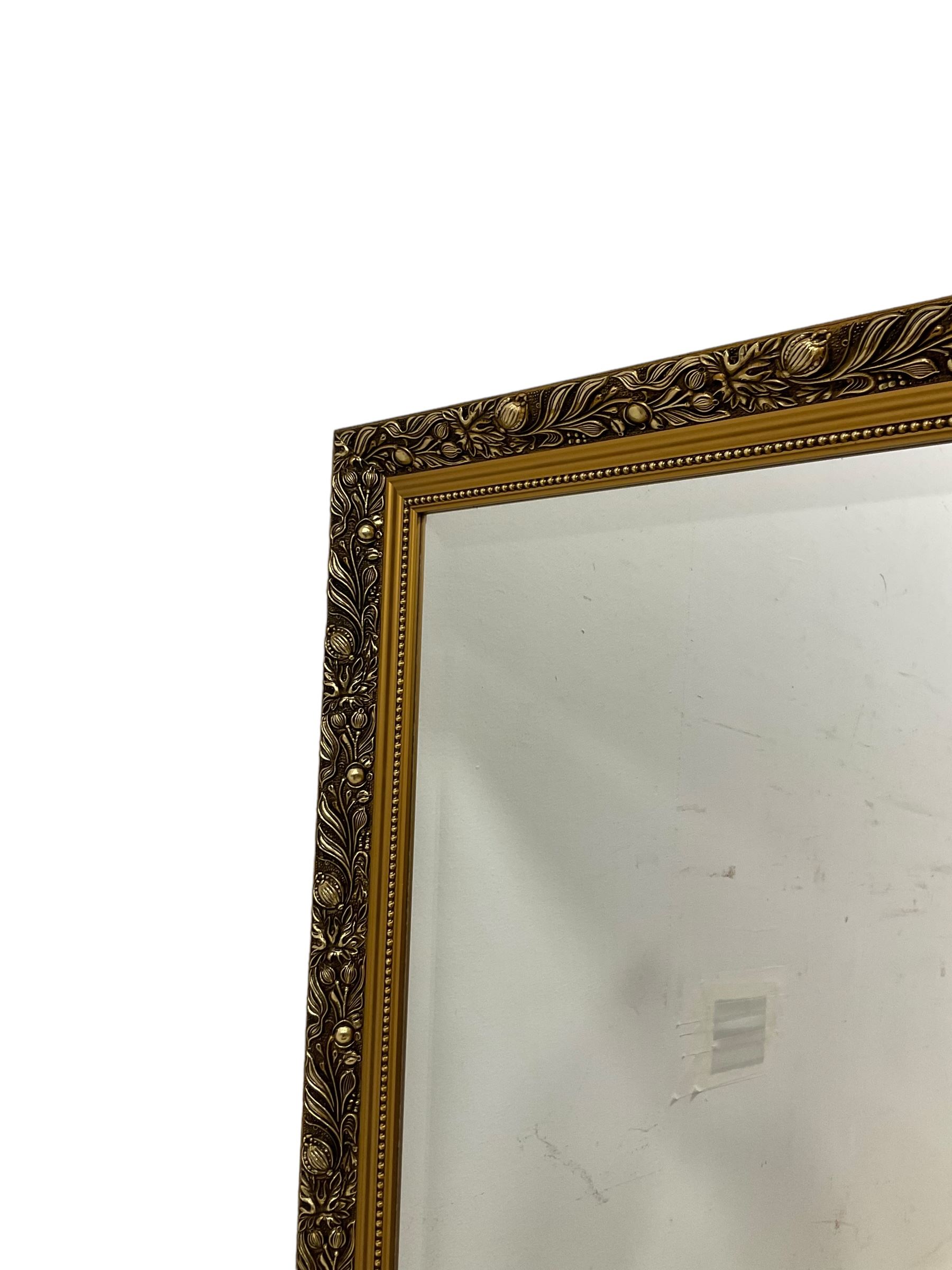 Large rectangular gilt framed wall mirror, decorated with trailing leafy branches and flowerheads, bevelled glass plate 