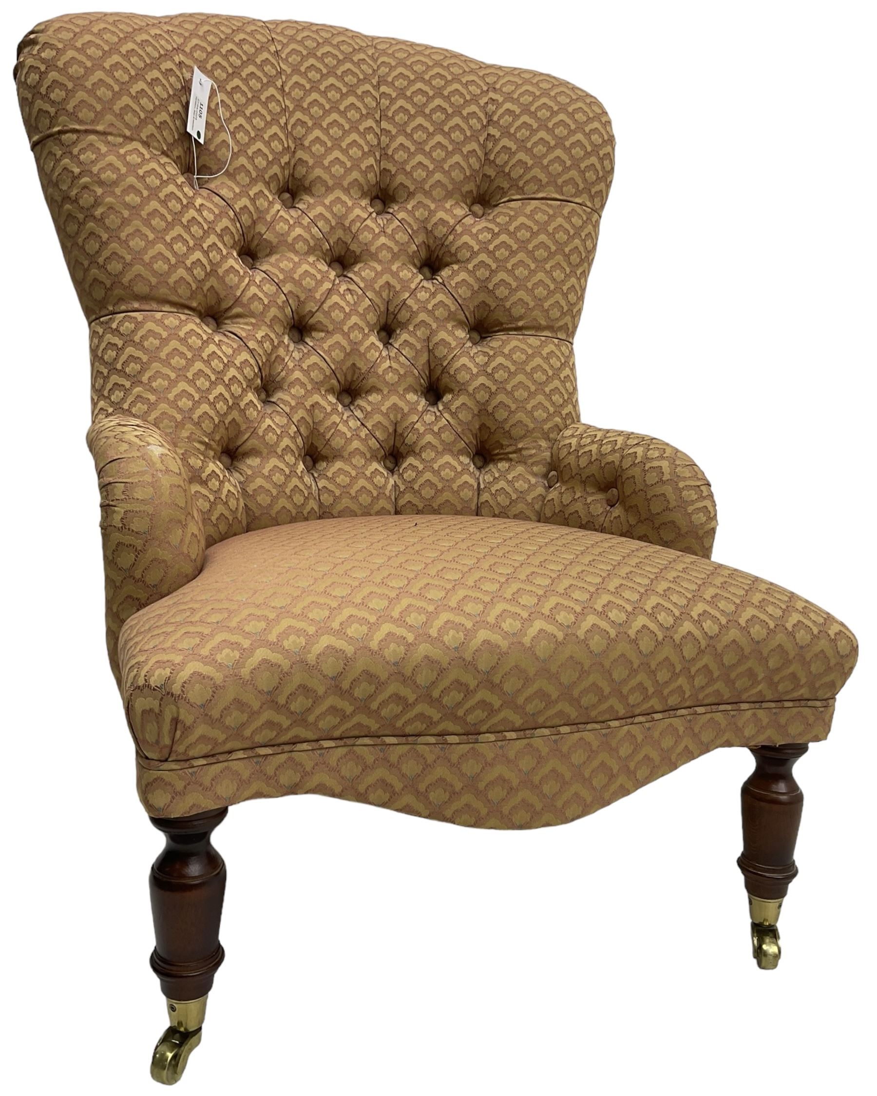 Victorian design armchair, buttoned back and spring seat upholstered in red and gold patterned fabric, shaped apron over turned mahogany supports with brass cups and castors