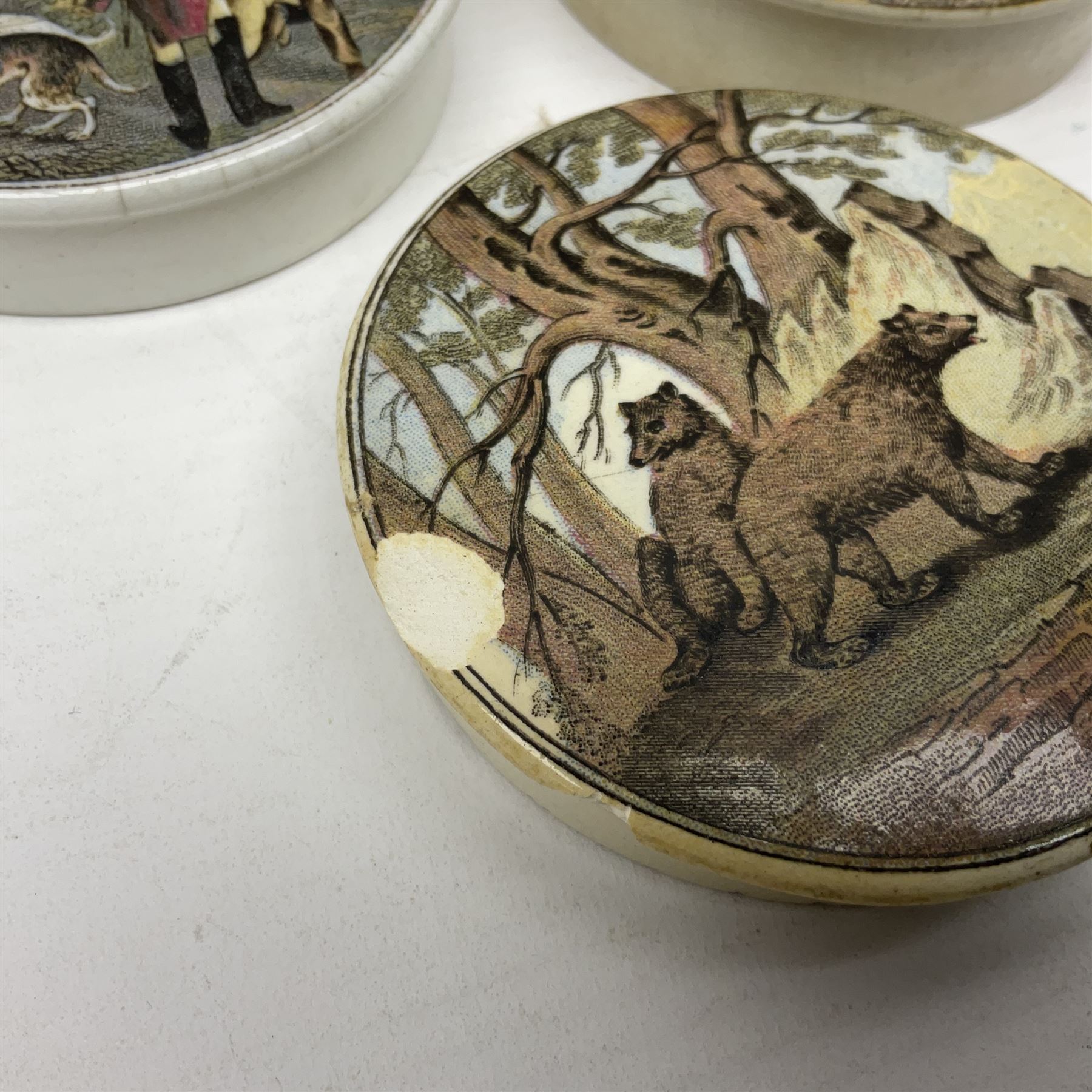 Six 19th century Prattware pot lids comprising 'The Village Wakes', three 'Bear on Rock', 'Shooting Bears' and 'Bear, Lion and Cock', two with associated bases, largest D9cm (6)