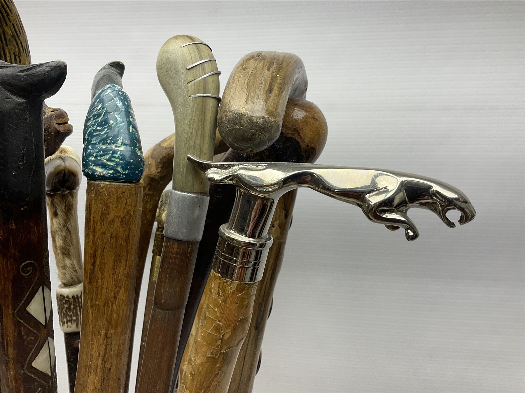 Oak barley twist stick stand, with a collection of walking sticks including examples with carved pommels, horn handles, silver collar etc, together with brass stick stand 