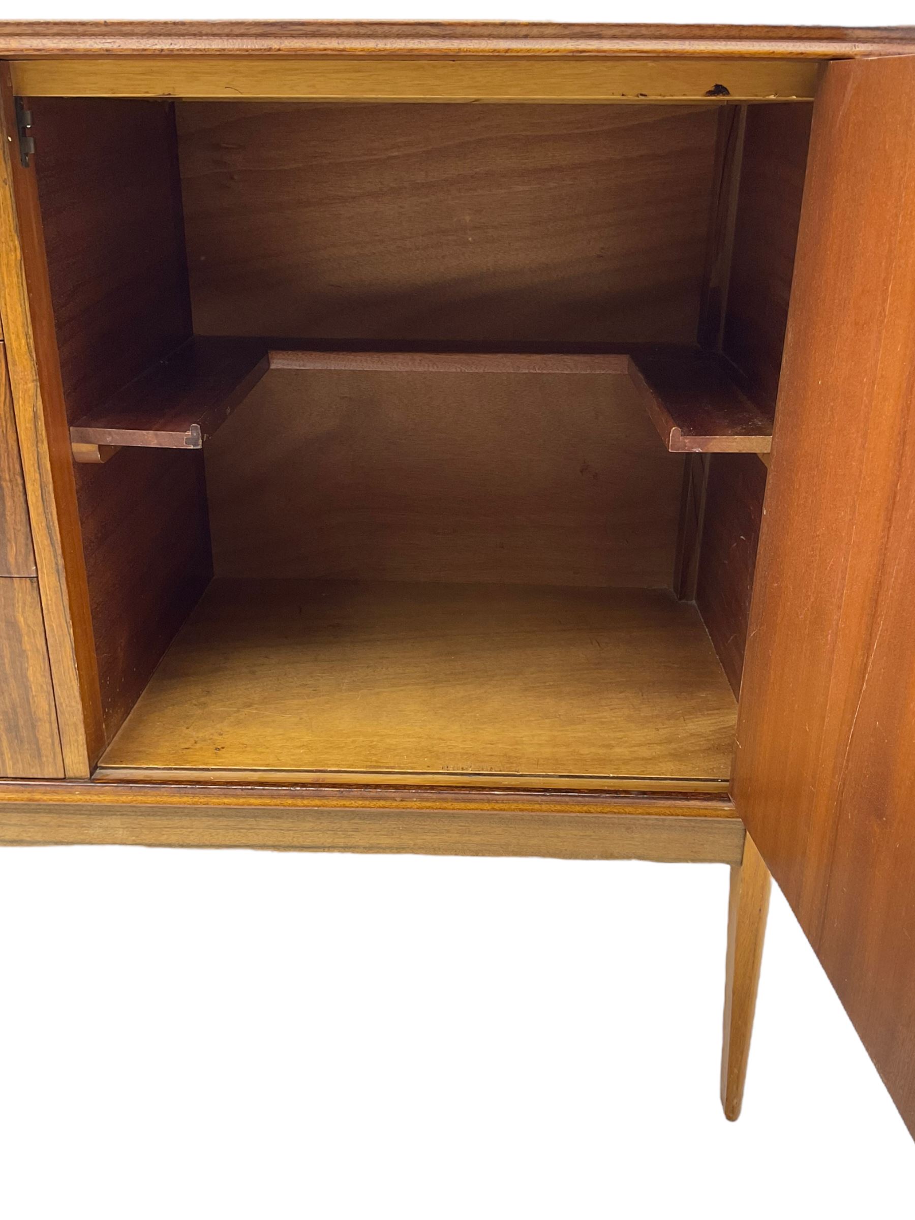 Mid 20th century teak sideboard, rectangular top with rounded corners over three central drawers, flanked by two cupboard doors enclosing shelves, raised on tapered supports