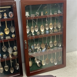 Five glazed wall display cases containing a selection of various souvenir spoons, comprising mostly silver plated examples. 