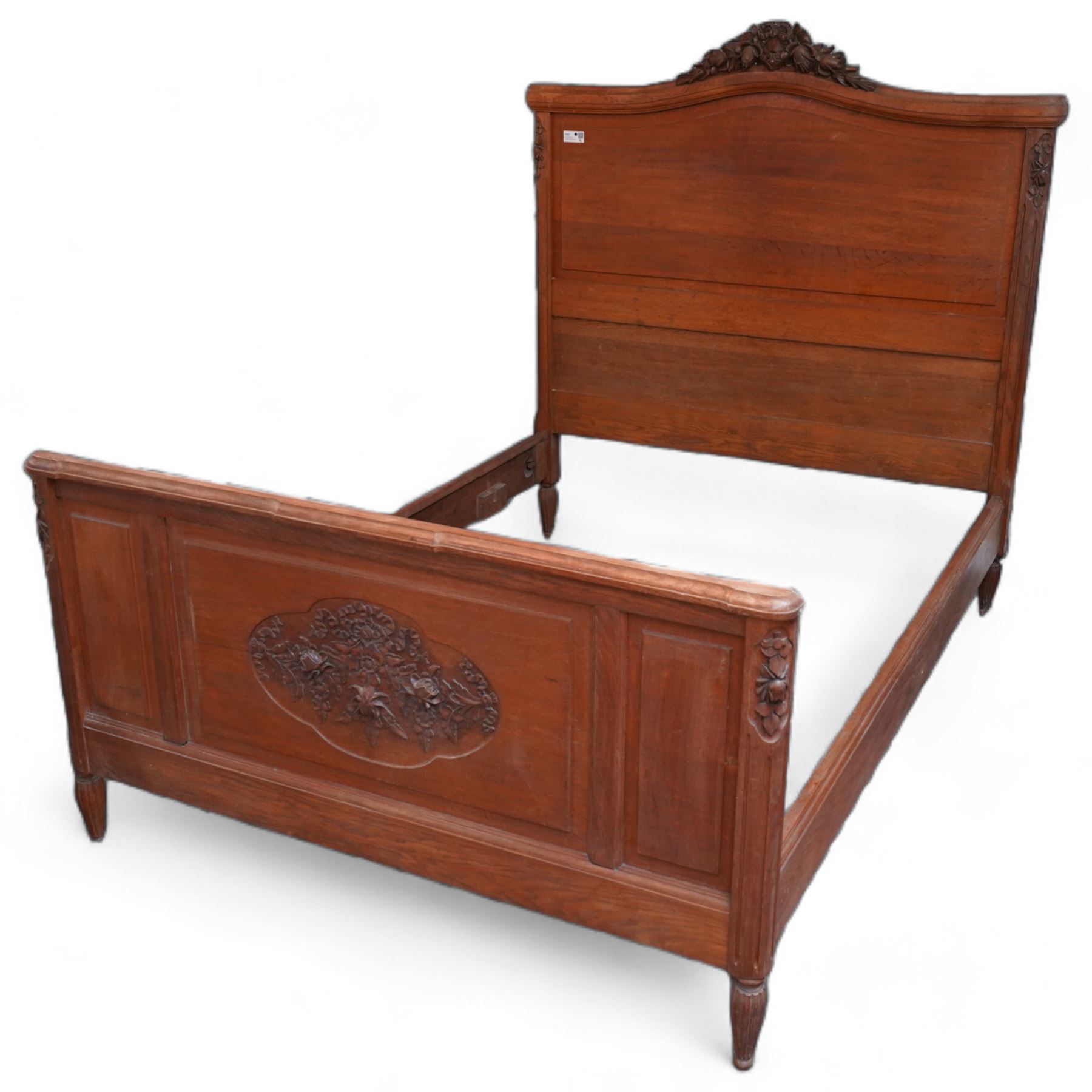 Late 19th century French oak double bedstead, headboard with shaped rail and carved pediment, carved footboard