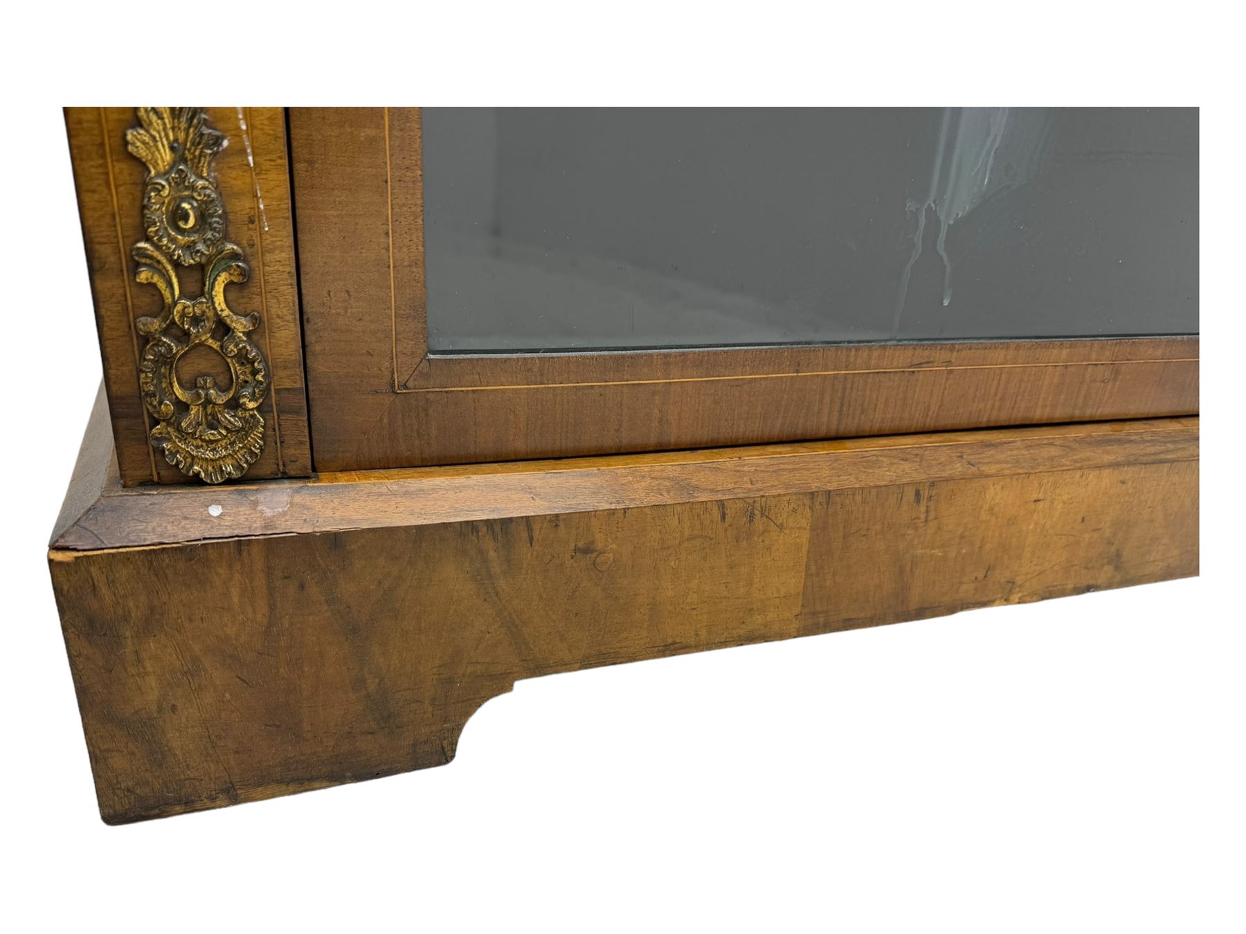 Late Victorian walnut pier cabinet, projecting cornice over frieze inlaid with foliate motifs, single glazed door flanked by ormolu mounts, enclosing shelved interior, on plinth base